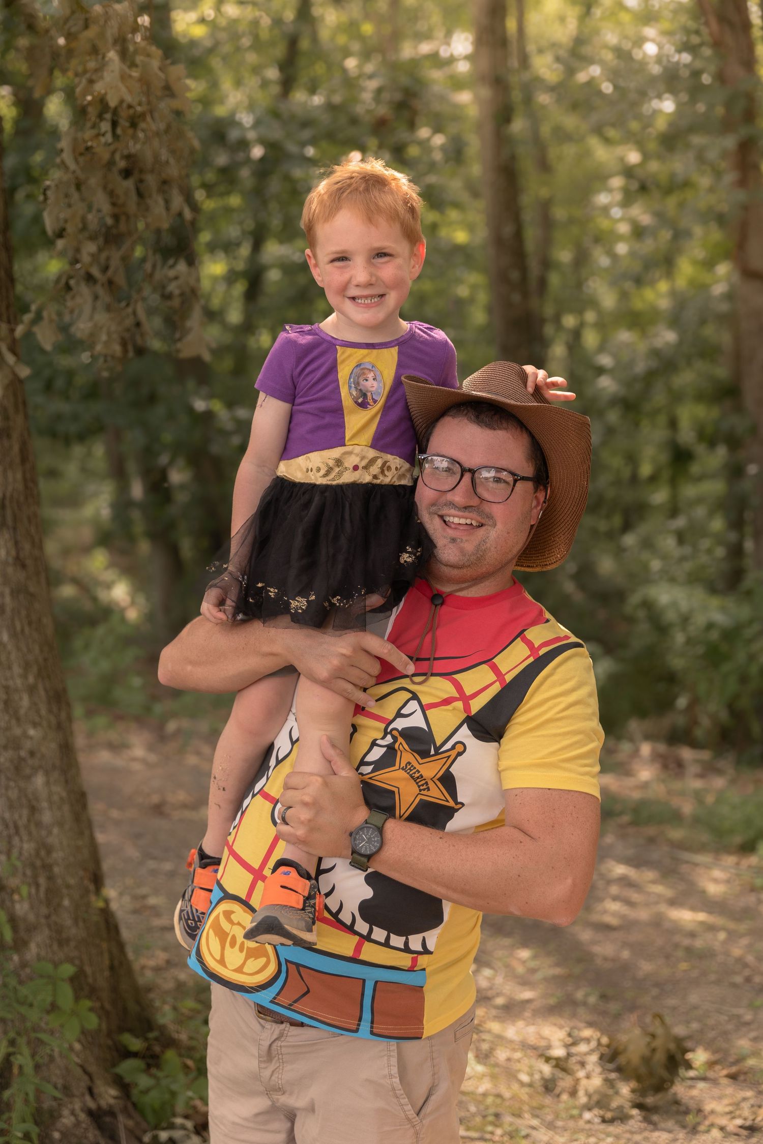 A fun Disney-themed photo featuring Woody from Toy Story and Rapunzel costumes in a forest setting.