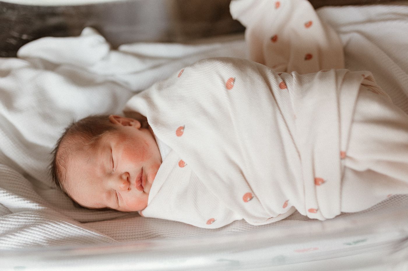 Peaceful newborn sleeps soundly while swaddled in white blanket in hospital for a fresh 48 session using story telling and film like editing