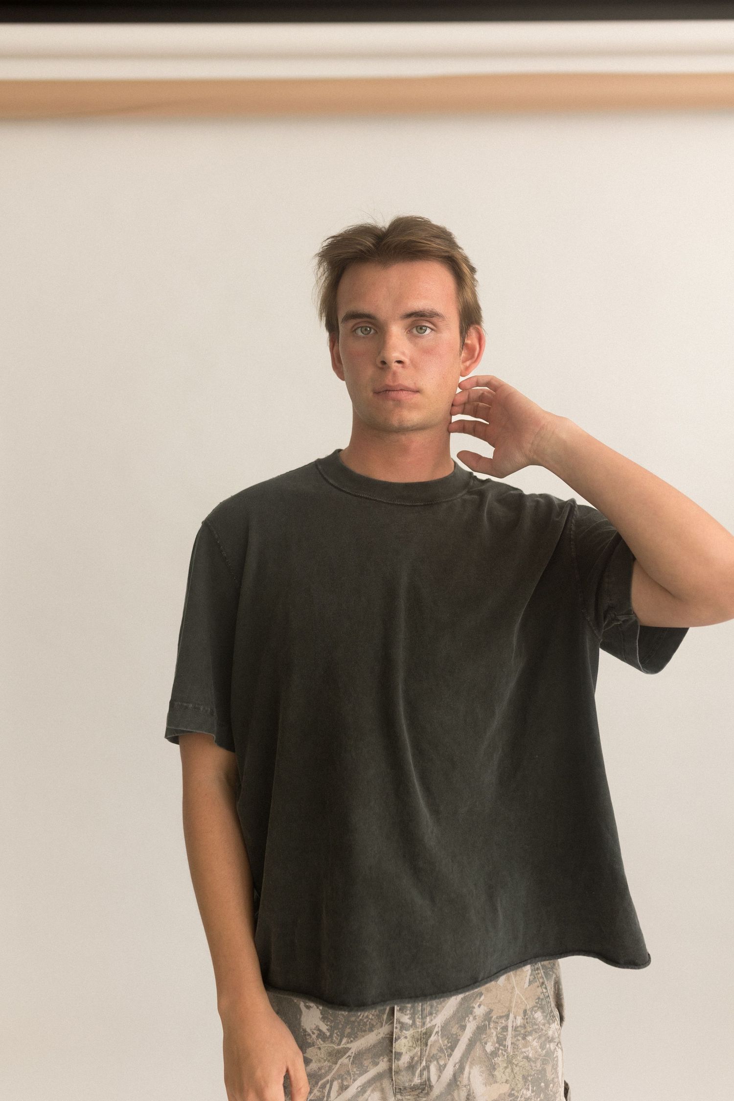 Portrait of person in black t-shirt against minimal white studio background.