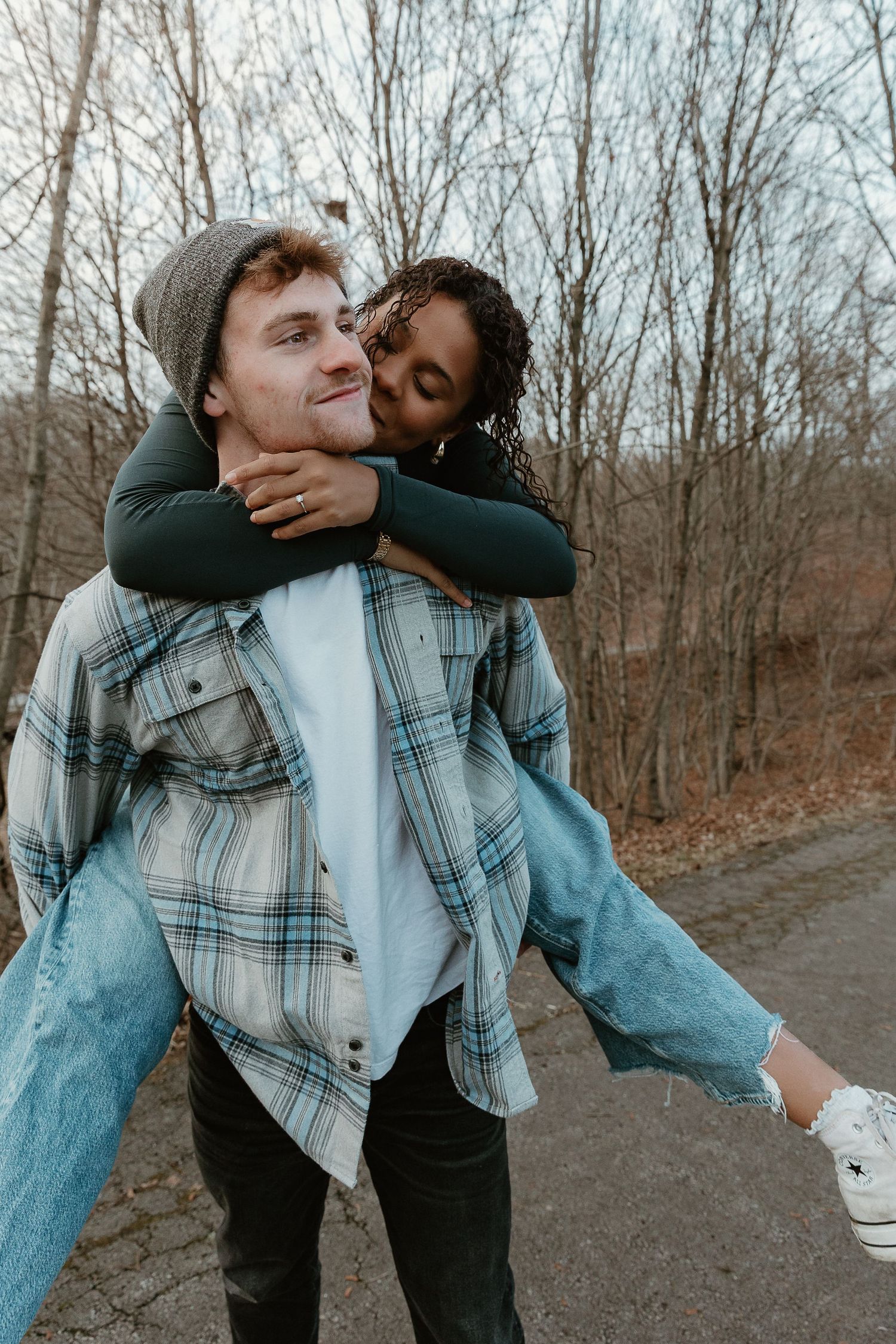 Playful piggyback ride through the woods, film-style edit with genuine laughter and carefree couple storytelling wearing laid back attire