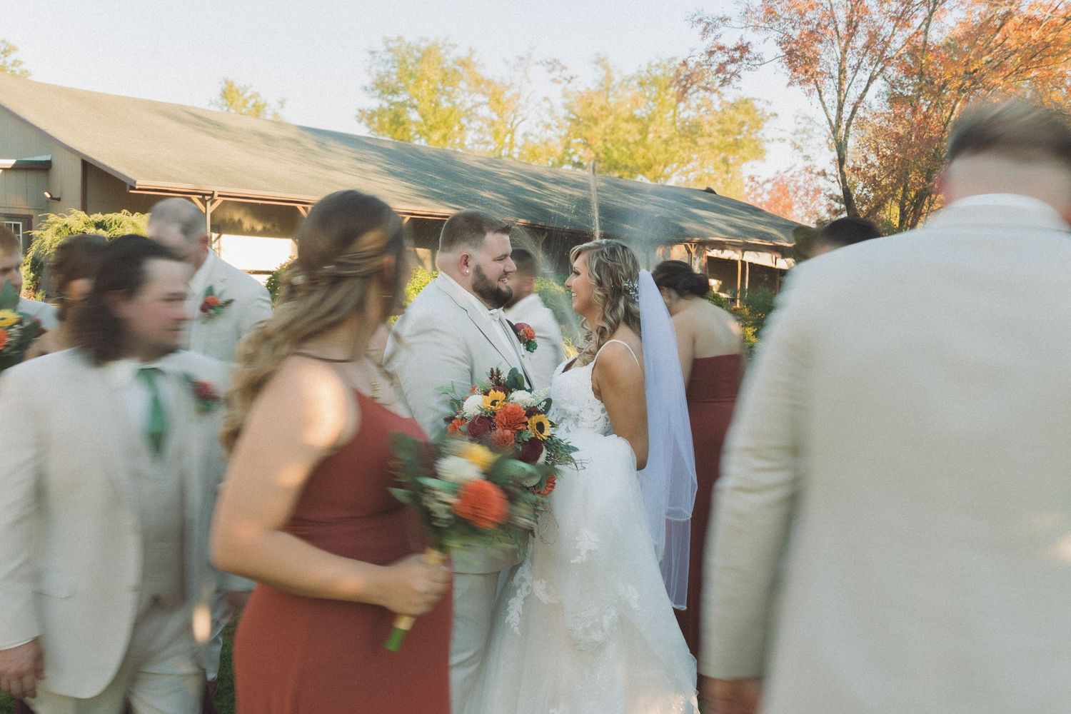 Motion blur capture of wedding party celebrating outdoors under autumn trees.