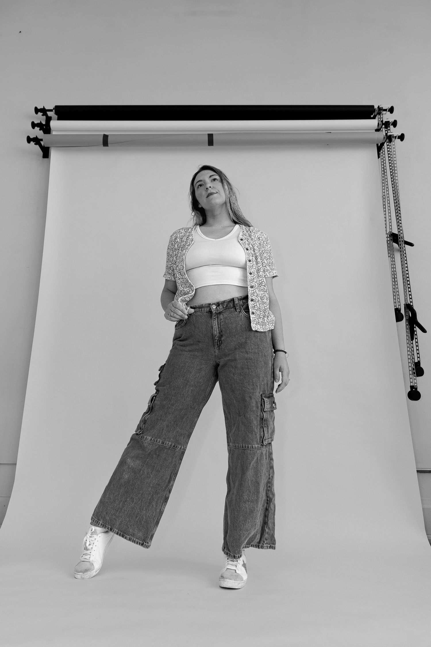 Fashion photo of person in wide-leg jeans and crop top against white studio backdrop.