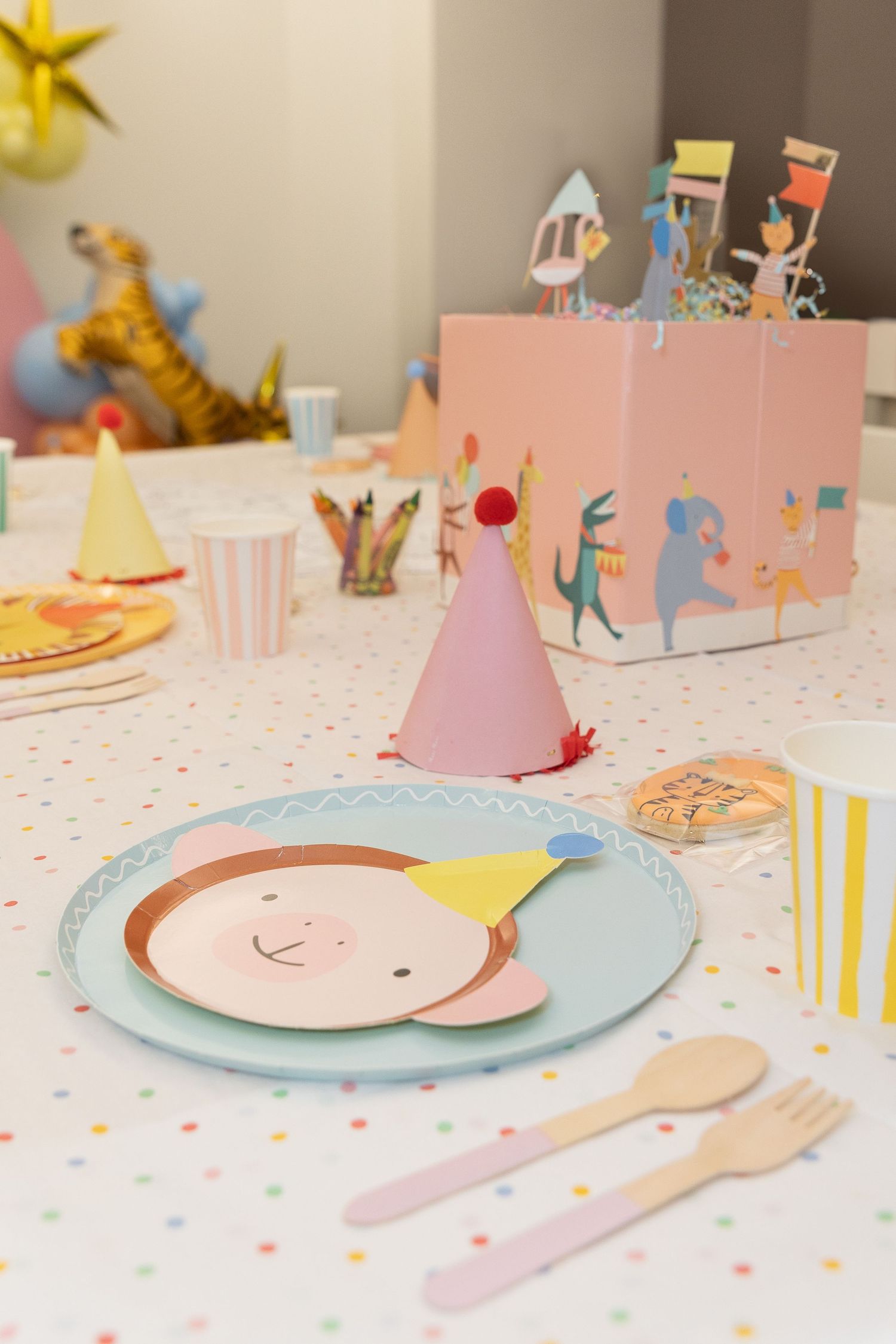 Whimsical birthday party table setting with colorful plates and party decorations.