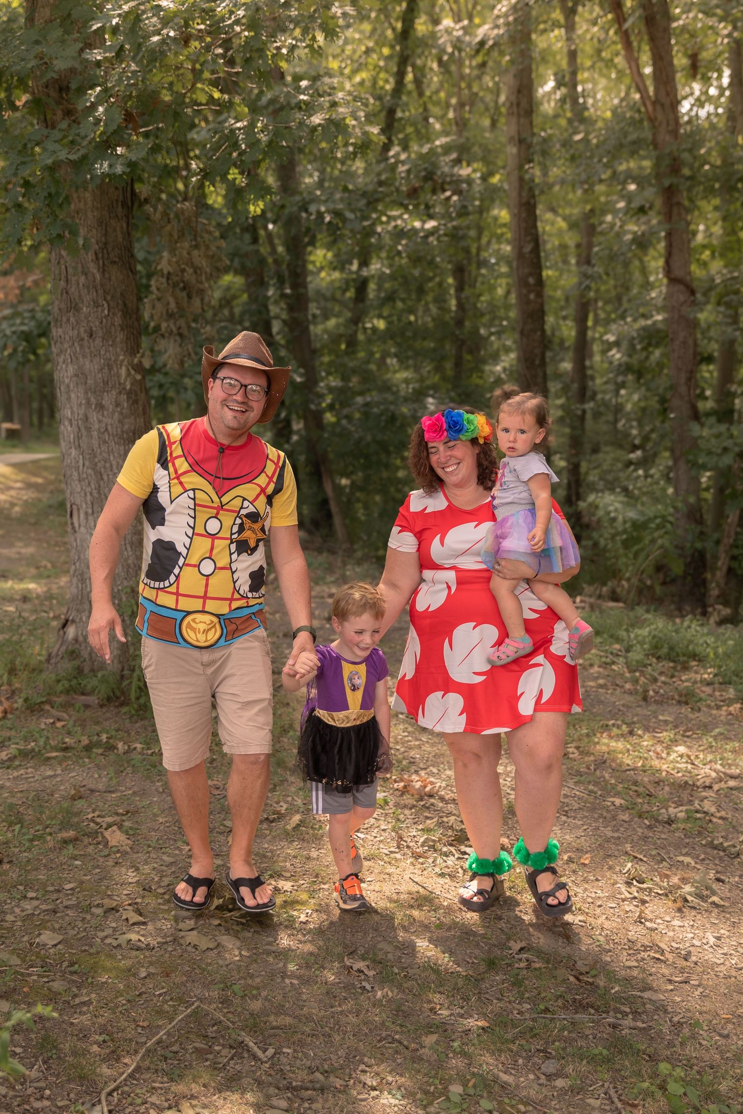 A family dressed in fun costumes walks along a forest path together on a sunny day.
