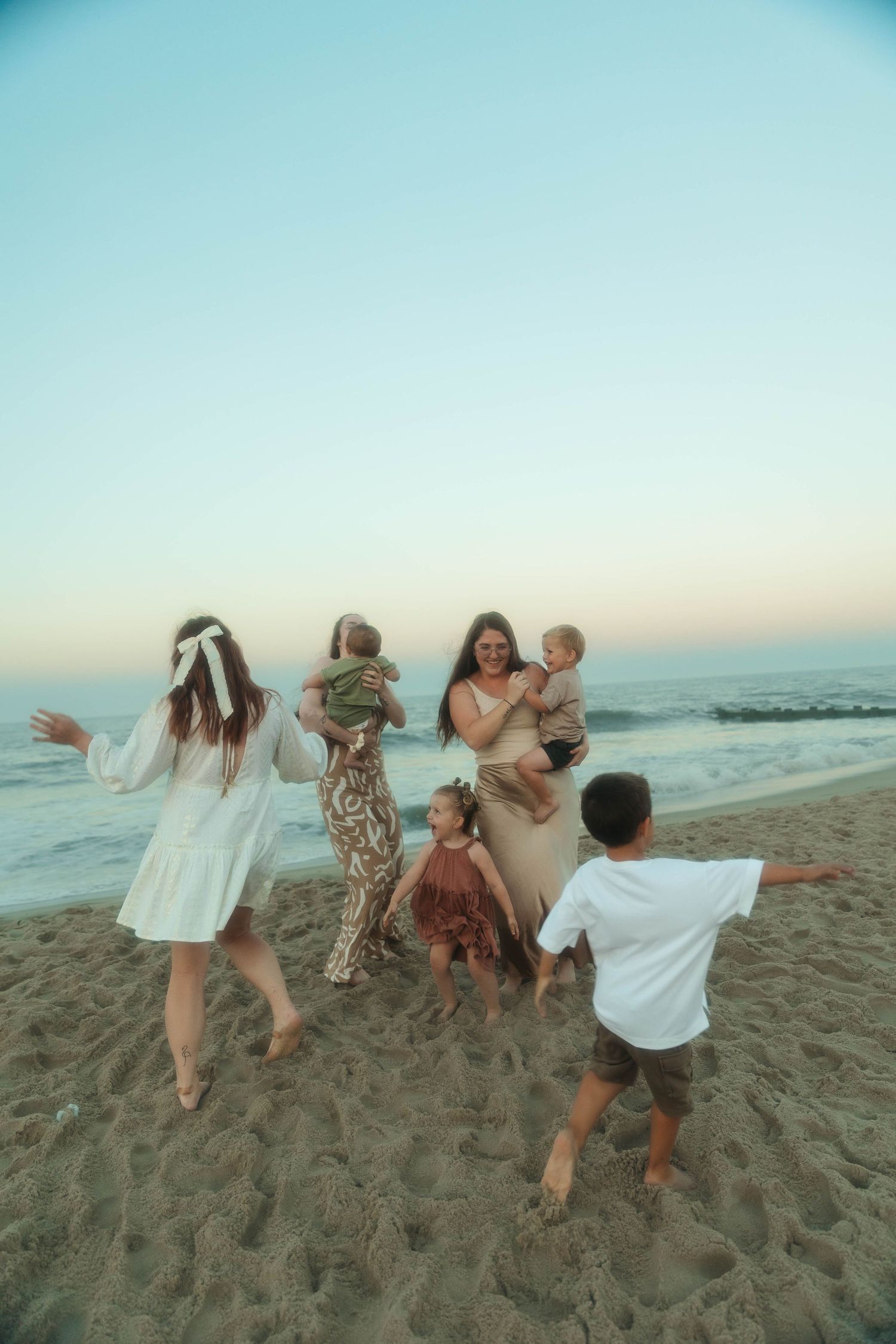 Group of friends enjoying sunset together on sandy beach with children.
