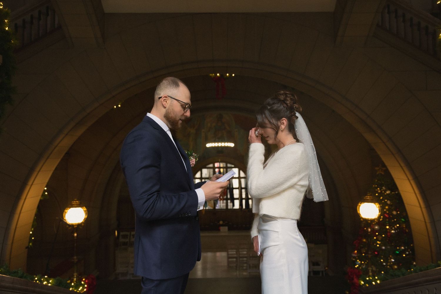 Wedding ceremony in an archway with romantic lighting and Christmas decorations.