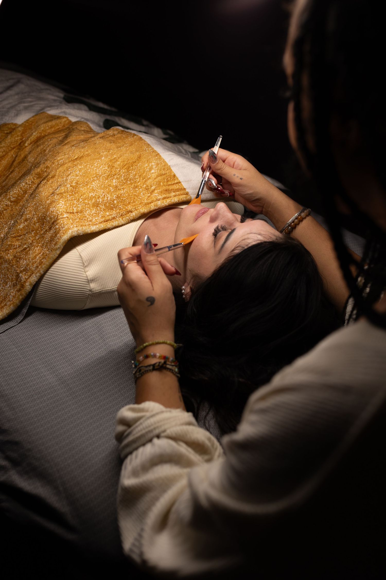 A beauty professional applying eyelash treatments during a lash service session.