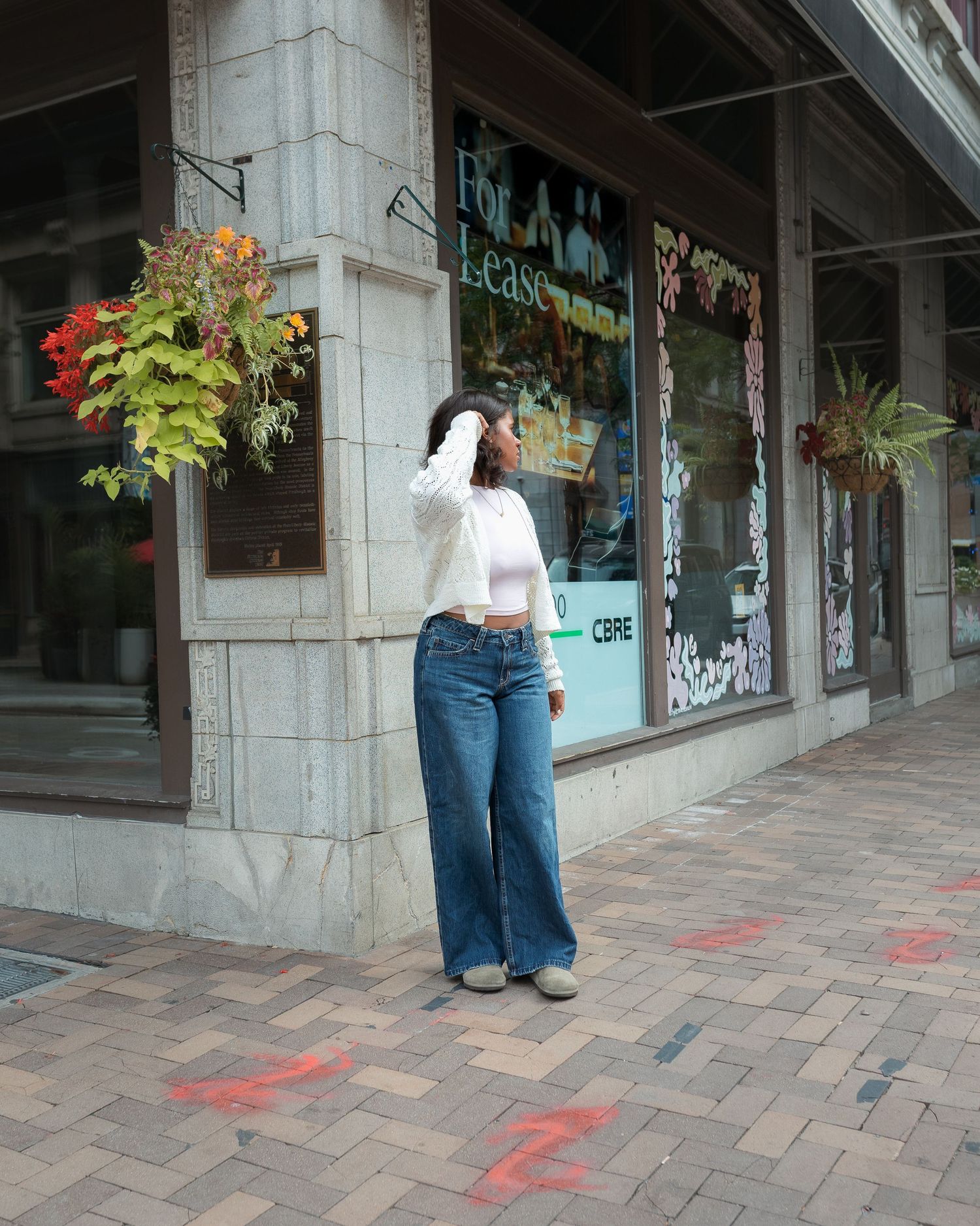 A series of connected images showing someone walking along a brick-paved sidewalk past storefronts with hanging flower baskets.