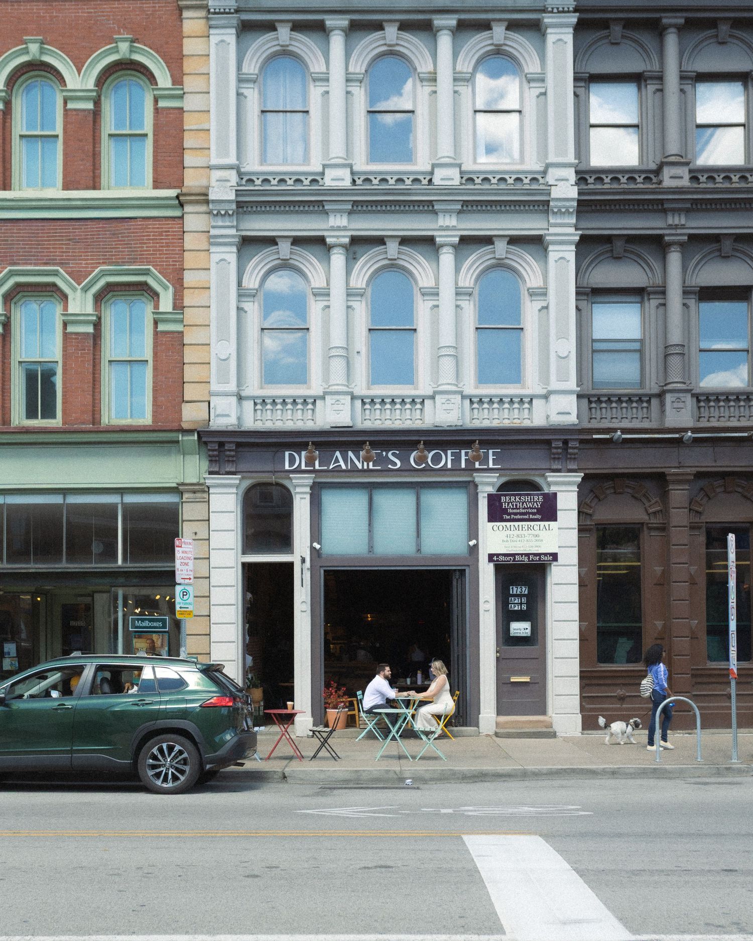 Historic brick building exterior with Delanc's Coffee signage and arched windows along a city street.