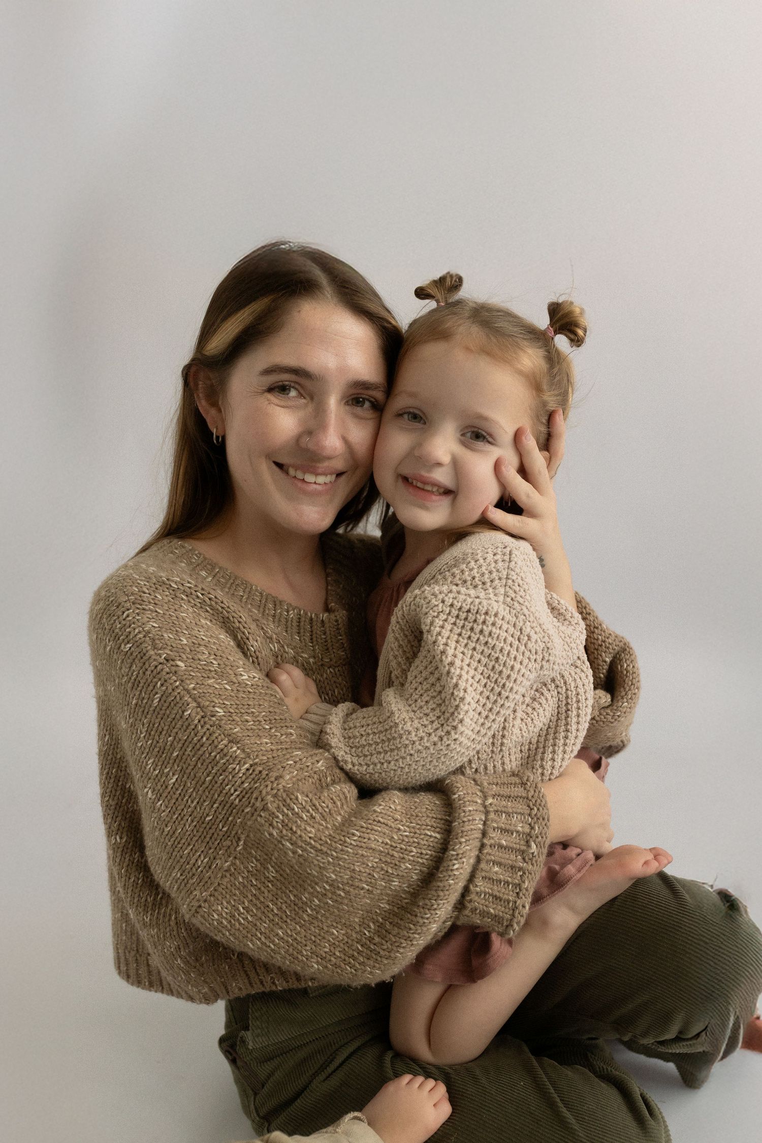 Heartwarming studio portrait of parent and child in matching knit sweaters.