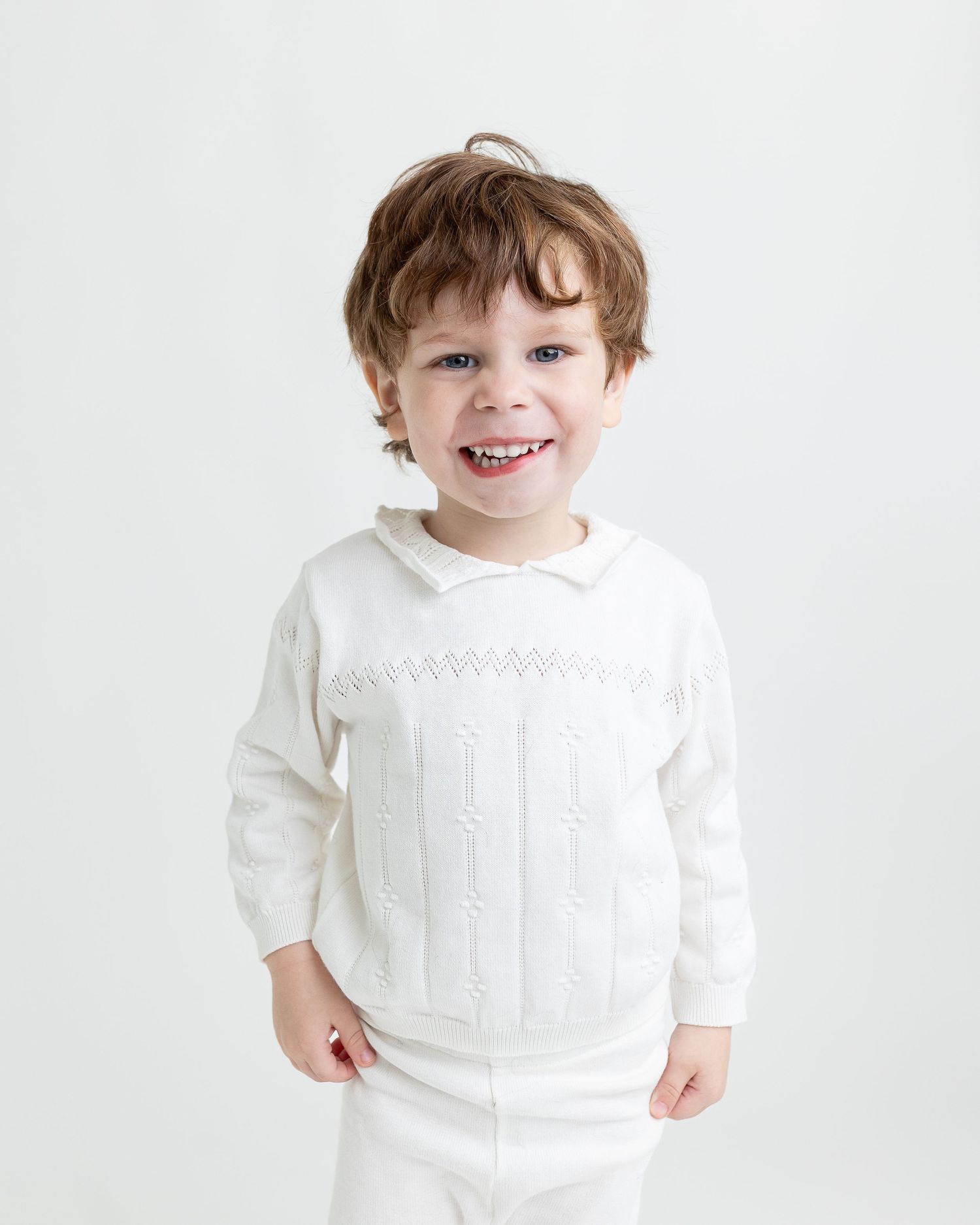 A child wearing a white knit sweater smiles and poses against a white background in a series of candid shots.