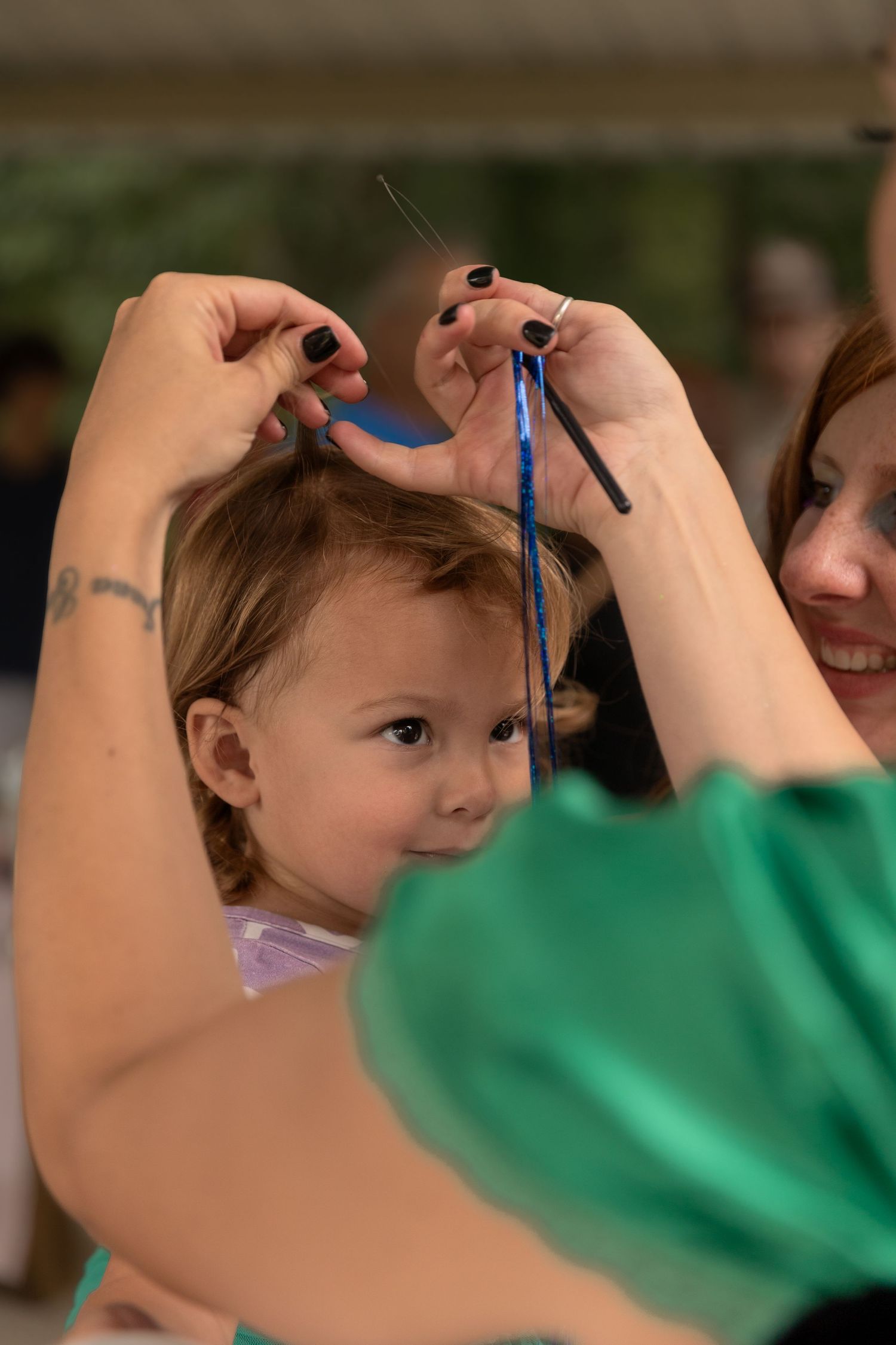 A child getting their hair styled with blue ribbons during a special celebration.