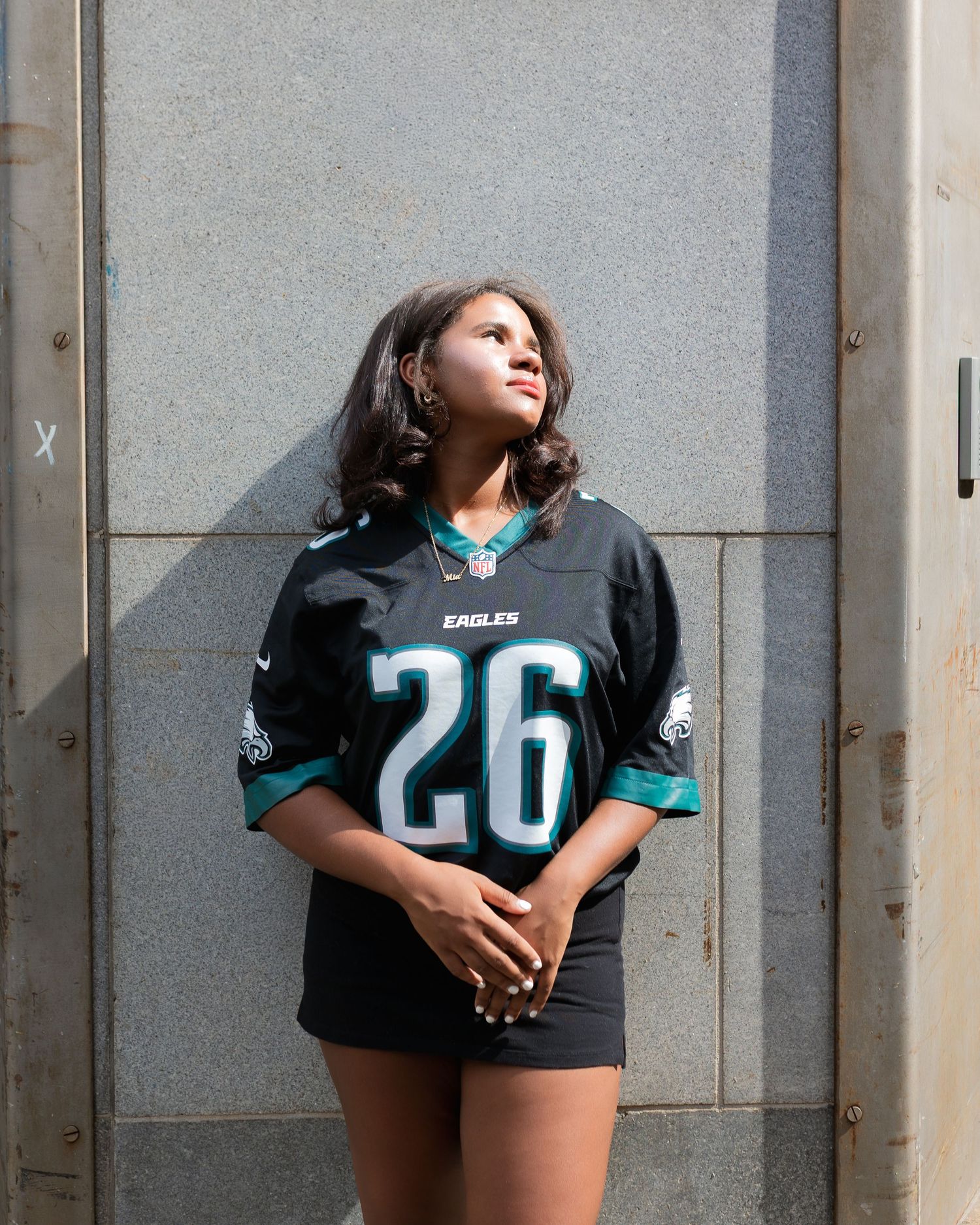 Person wearing a black Jacksonville Jaguars jersey poses against a gray wall in three different poses.