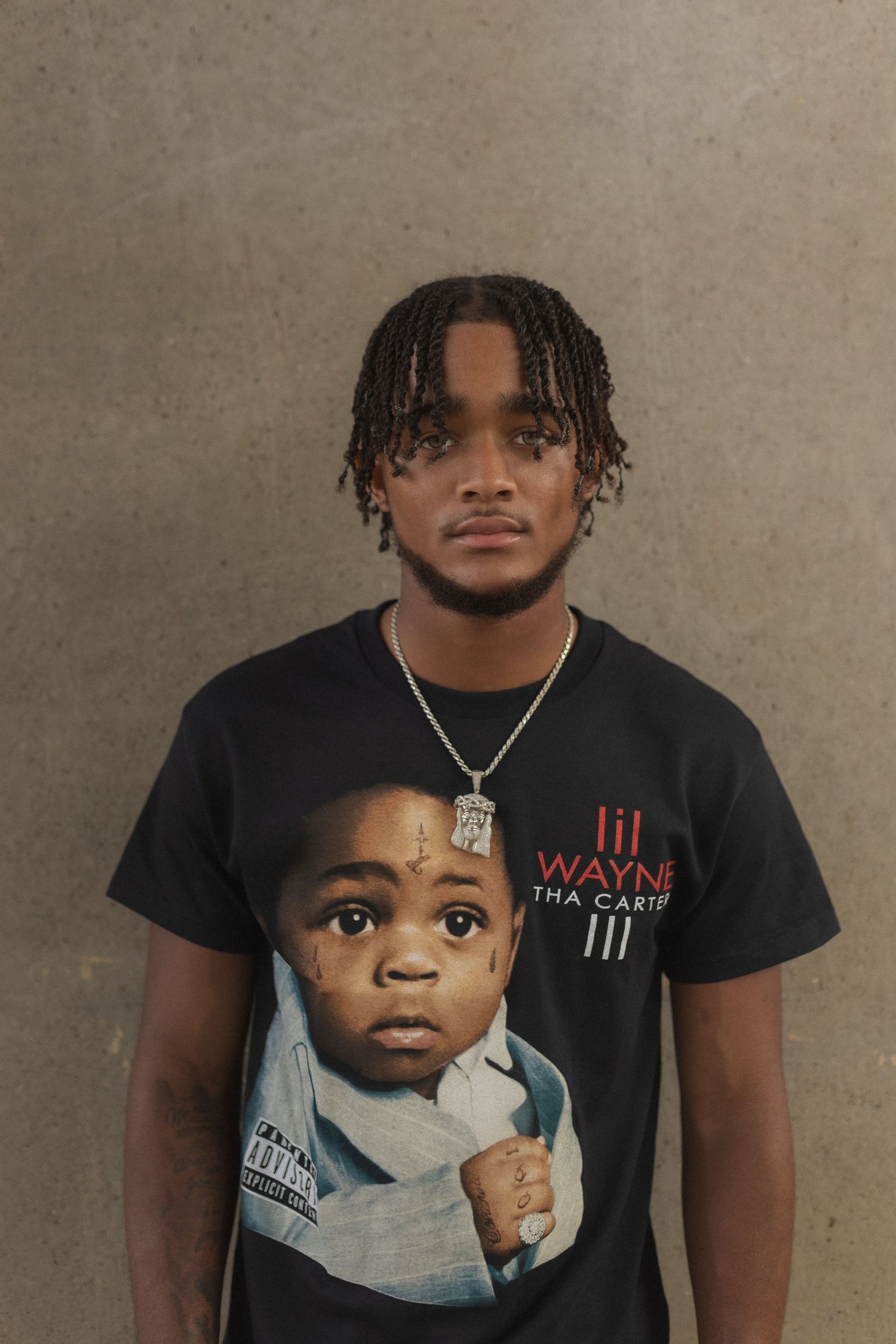 Studio portrait in Lil Wayne graphic t-shirt against brown backdrop.