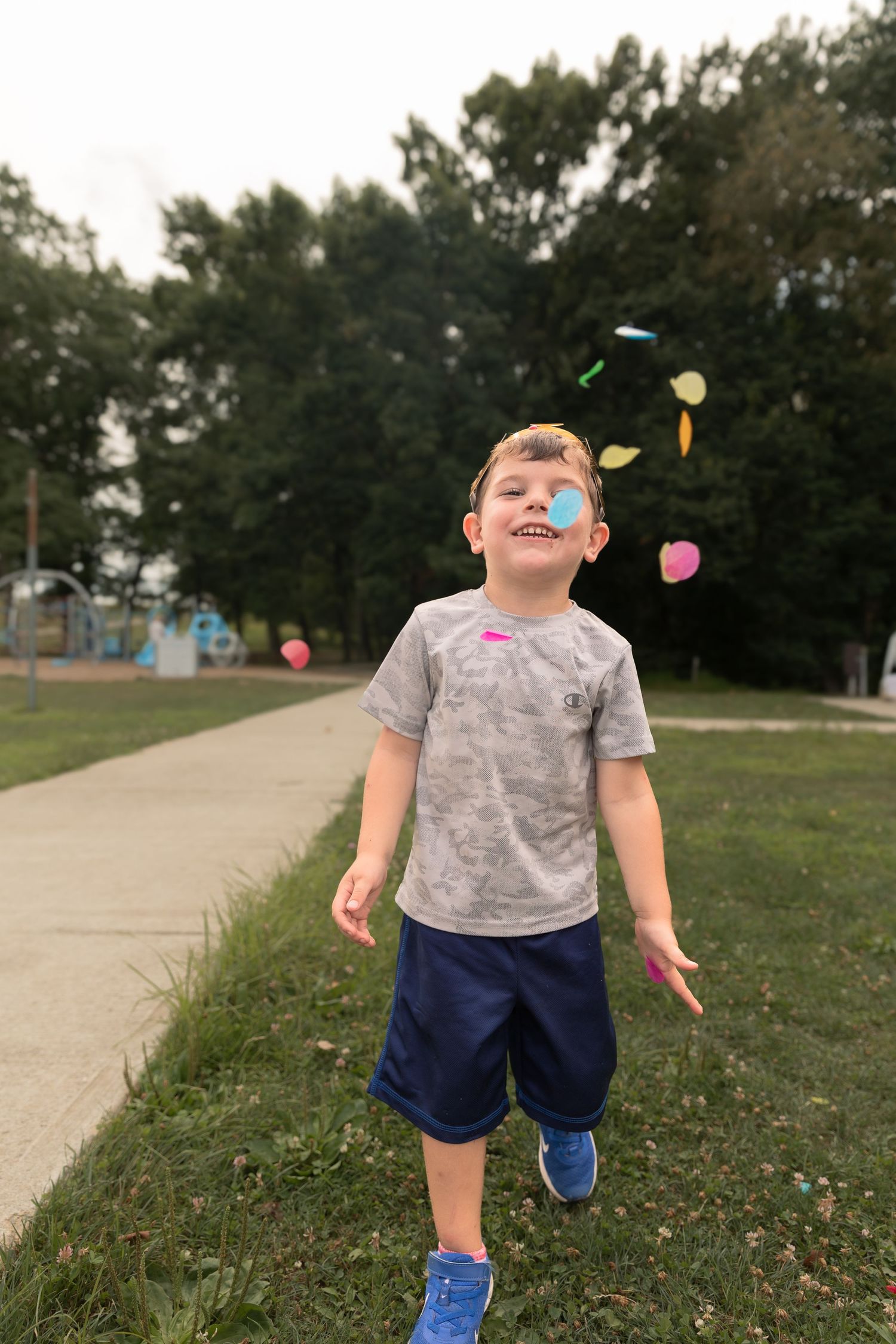 A child plays outdoors with colorful bubbles floating in the air on a summer day.