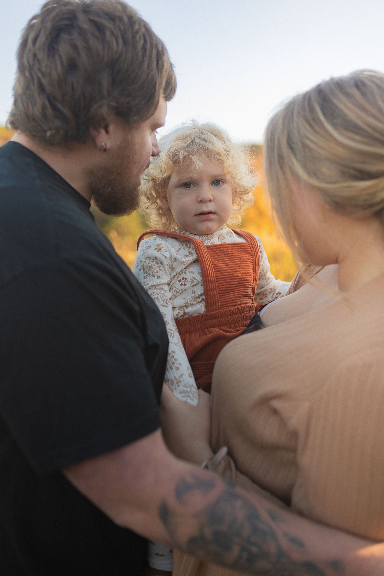 An intimate family moment captured in warm sunlight against a natural backdrop.