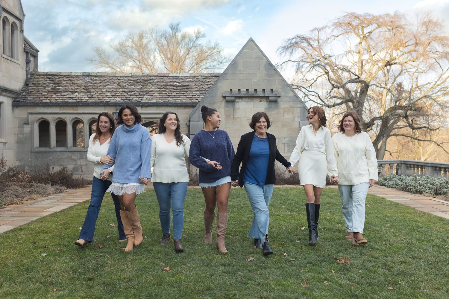 Group of friends in coordinated white and blue outfits walking together outside a stone building.