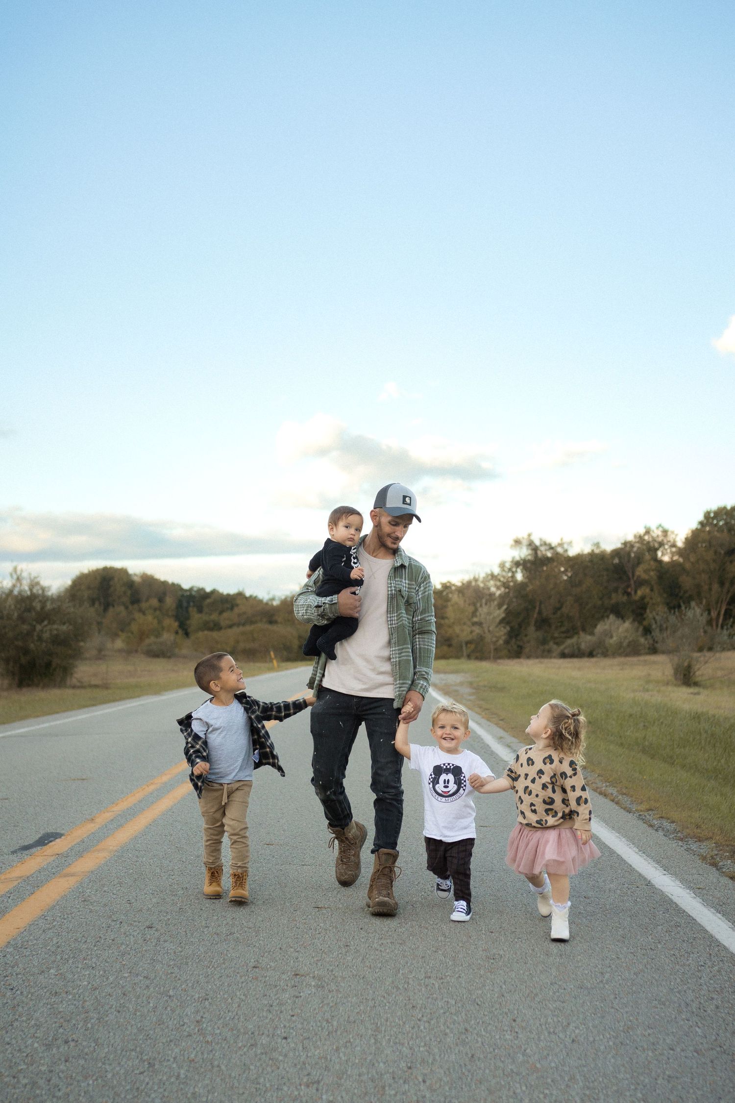 Family walking together on a country road during golden hour.