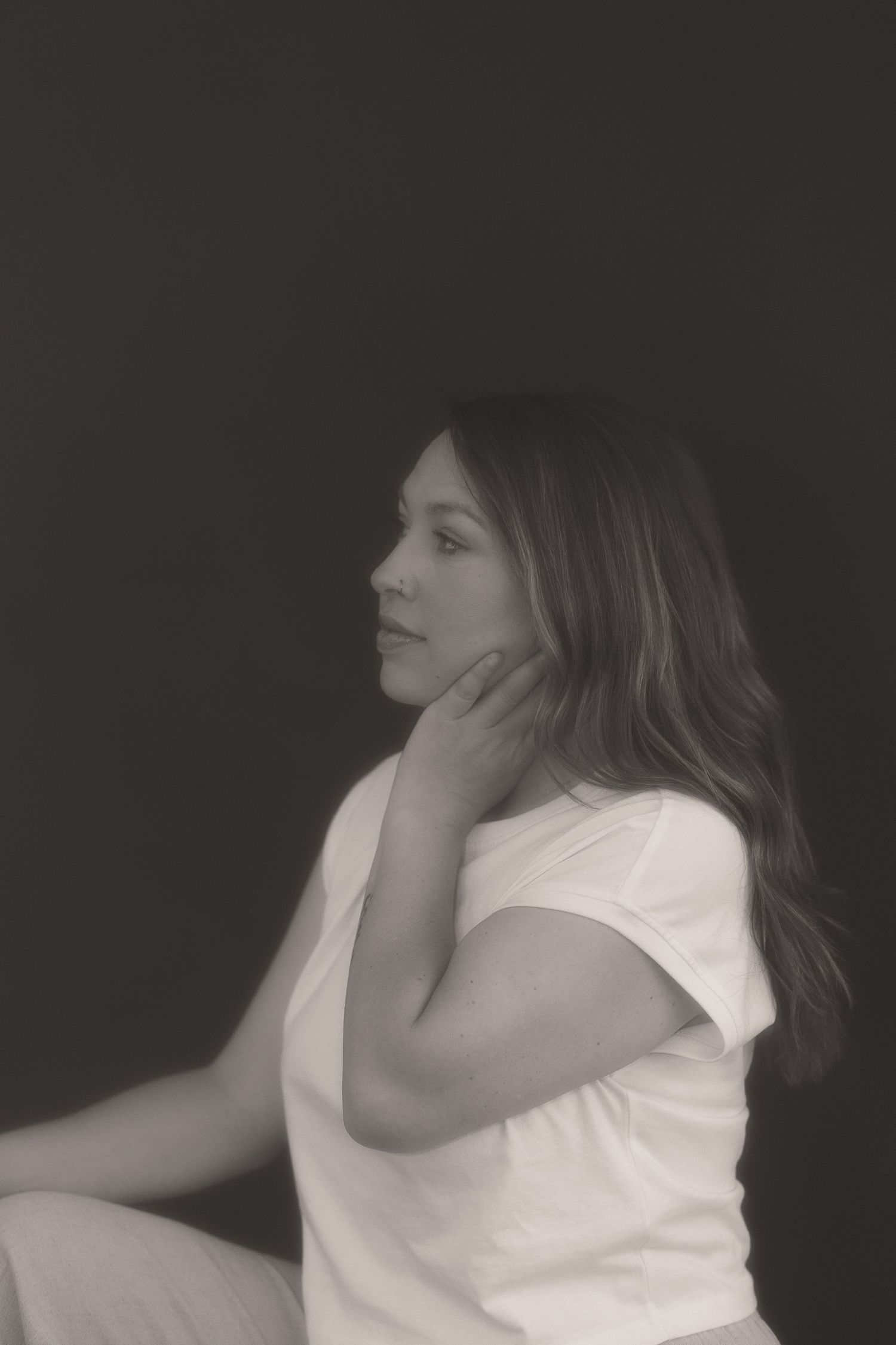 Artistic black and white profile portrait against dark background.