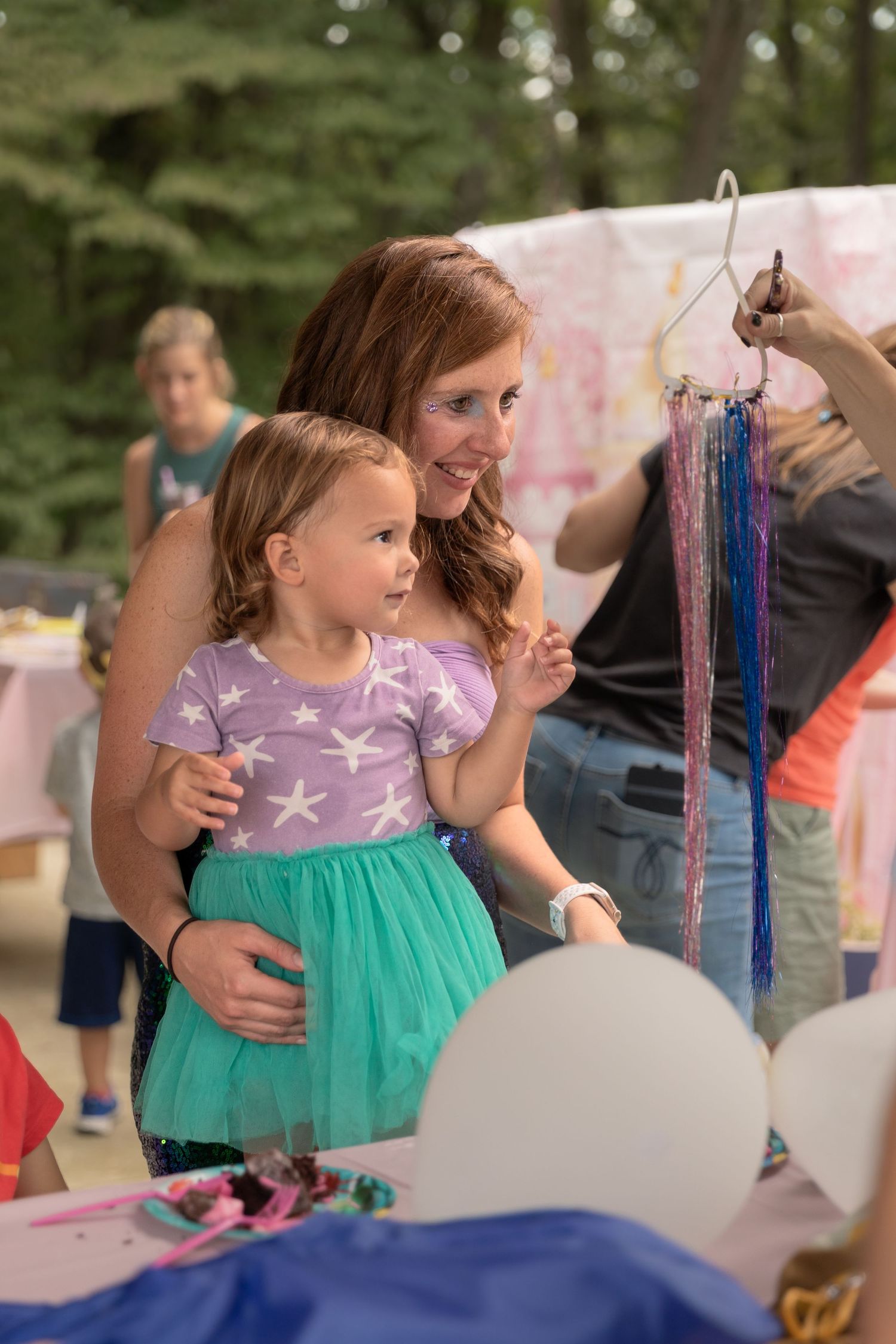 A magical party moment with sparkly decorations, balloons, and a purple and turquoise dress.