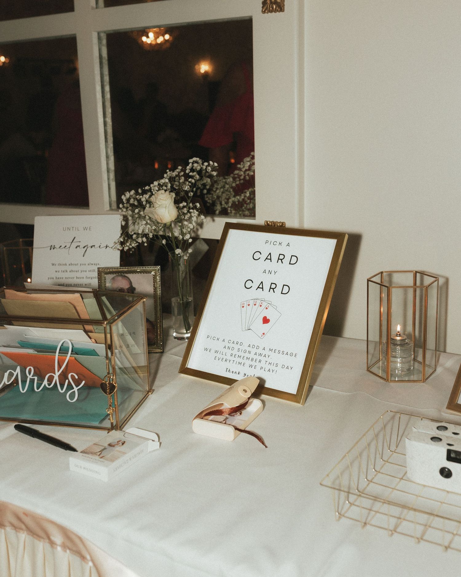 Wedding reception table setup with card displays and decorative elements on white tablecloths.