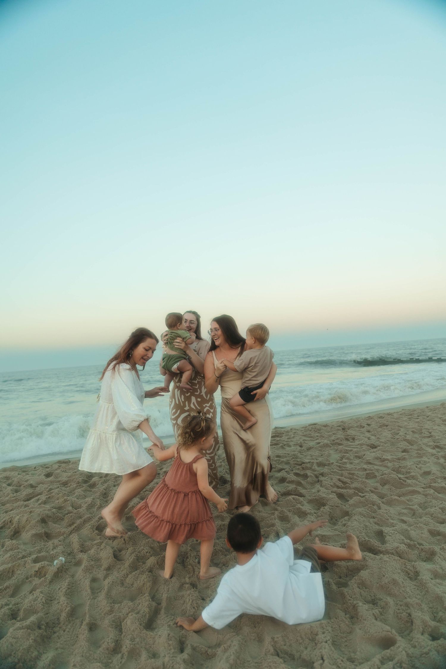 Candid moment of friends dancing and playing on beach at sunset.