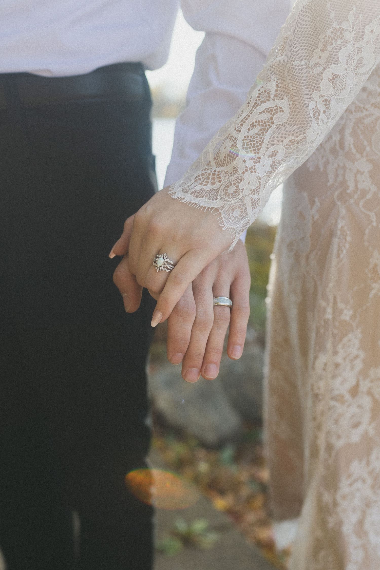 Close-up of wedding rings and lace detail on bride's sleeve.