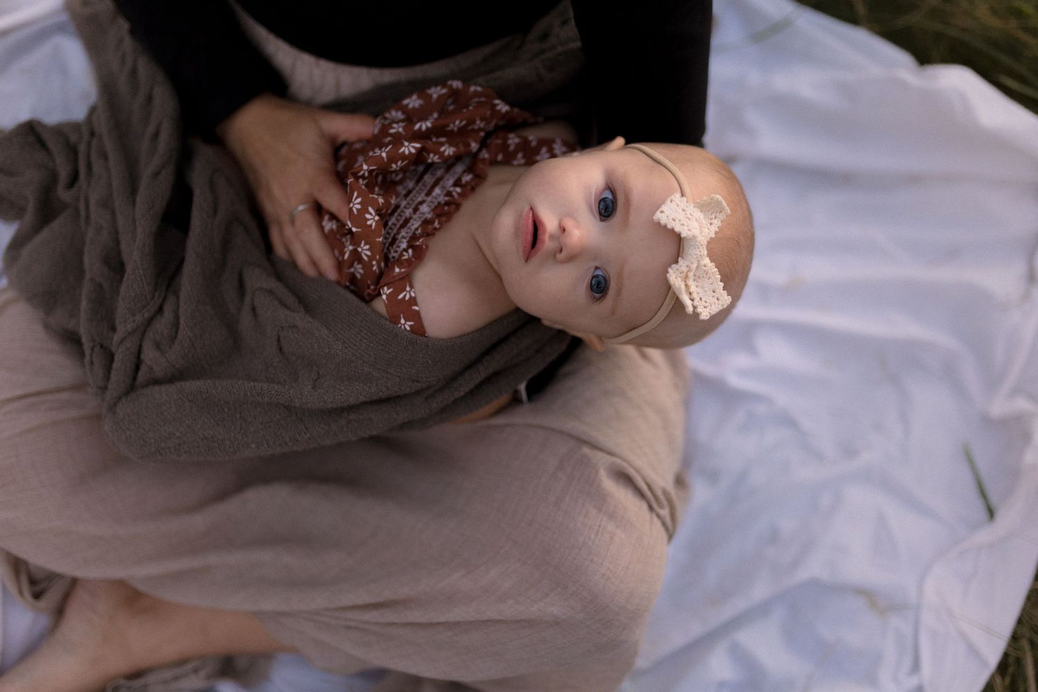A baby lying on a blanket wearing band-aids on their face.