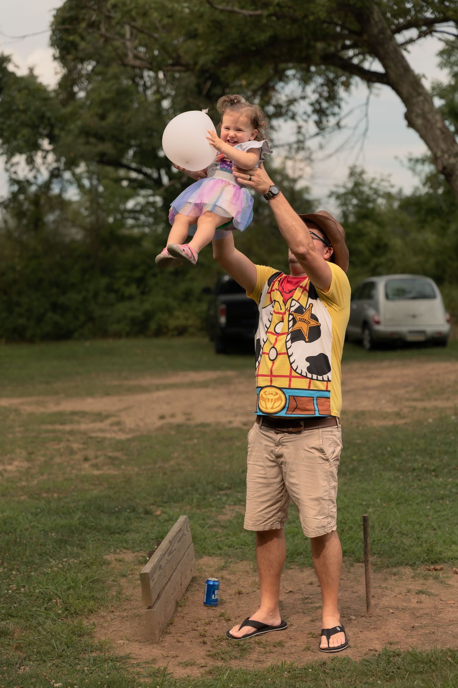 A special moment captured as a child is lifted into the air while playing with balloons outdoors.