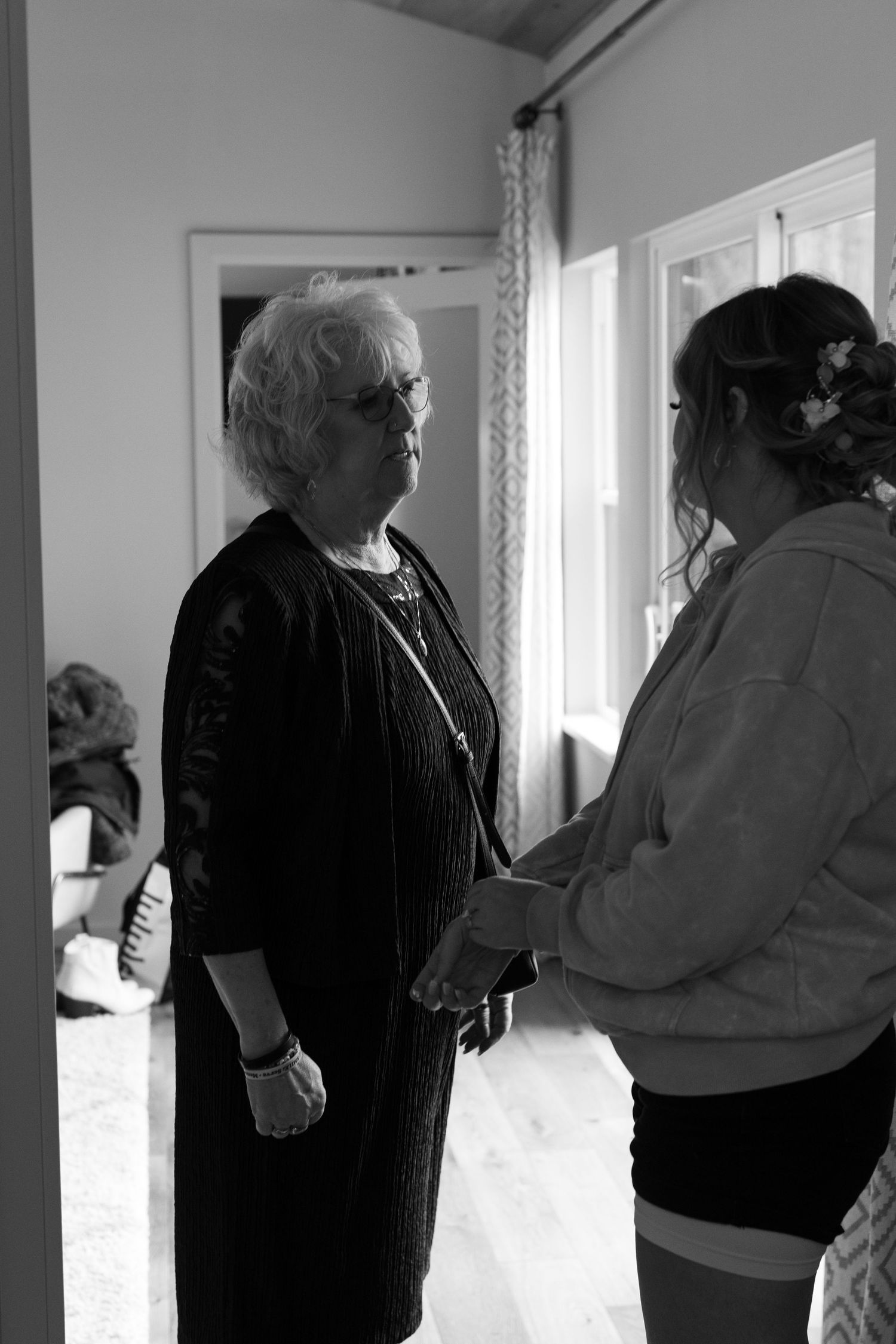 Black and white photo of an elderly woman holding hands with a young woman in an emotional moment.