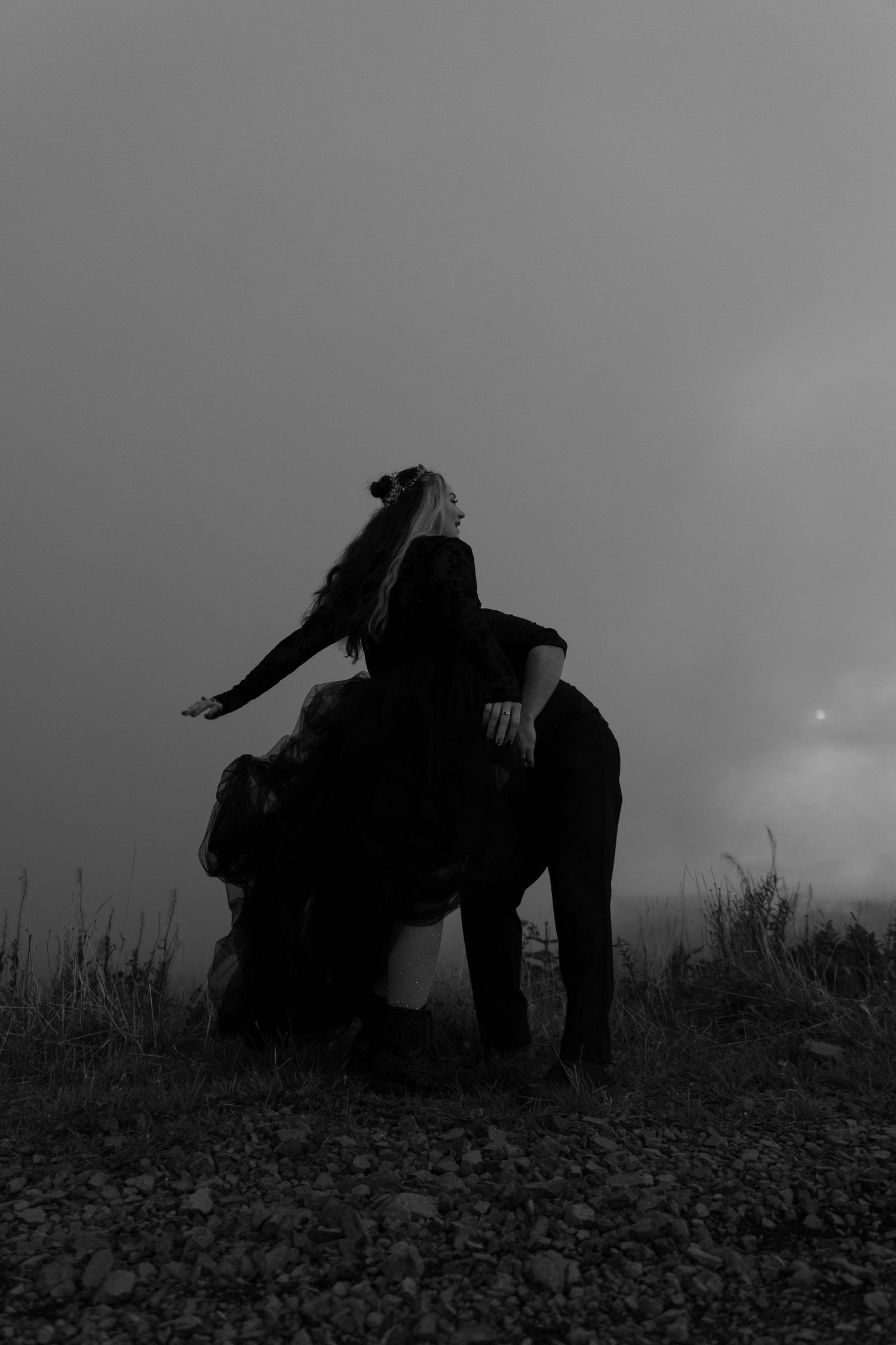 Black and white photo of a couple sitting together on a foggy hilltop at night.