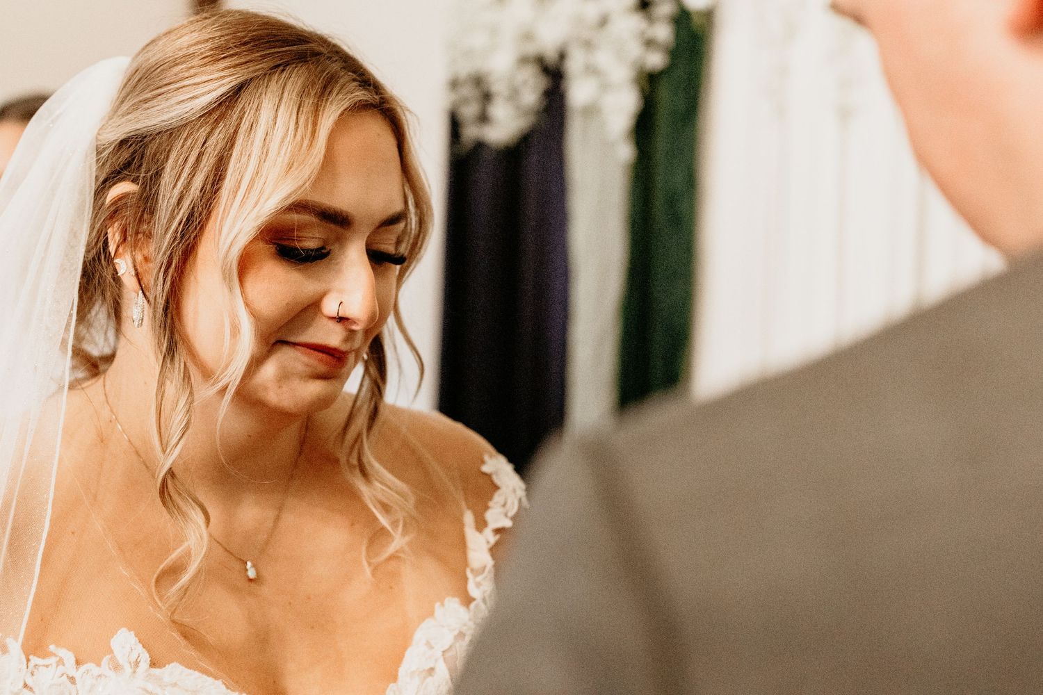 Close-up of emotional bride in lace veil and gown during intimate wedding ceremony exchange of vows.