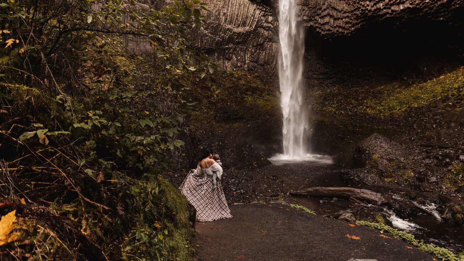Couple wrapped in a blanket embracing in front of a stunning cascading waterfall.