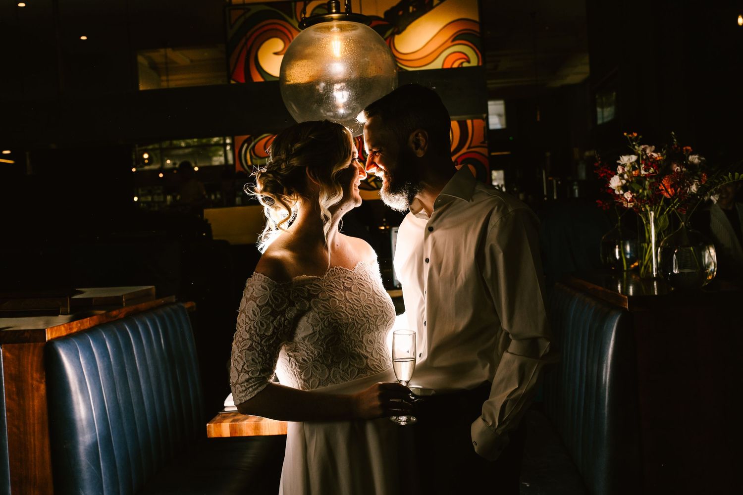 Couple sharing a romantic moment in a dimly lit bar, illuminated by a warm pendant light.