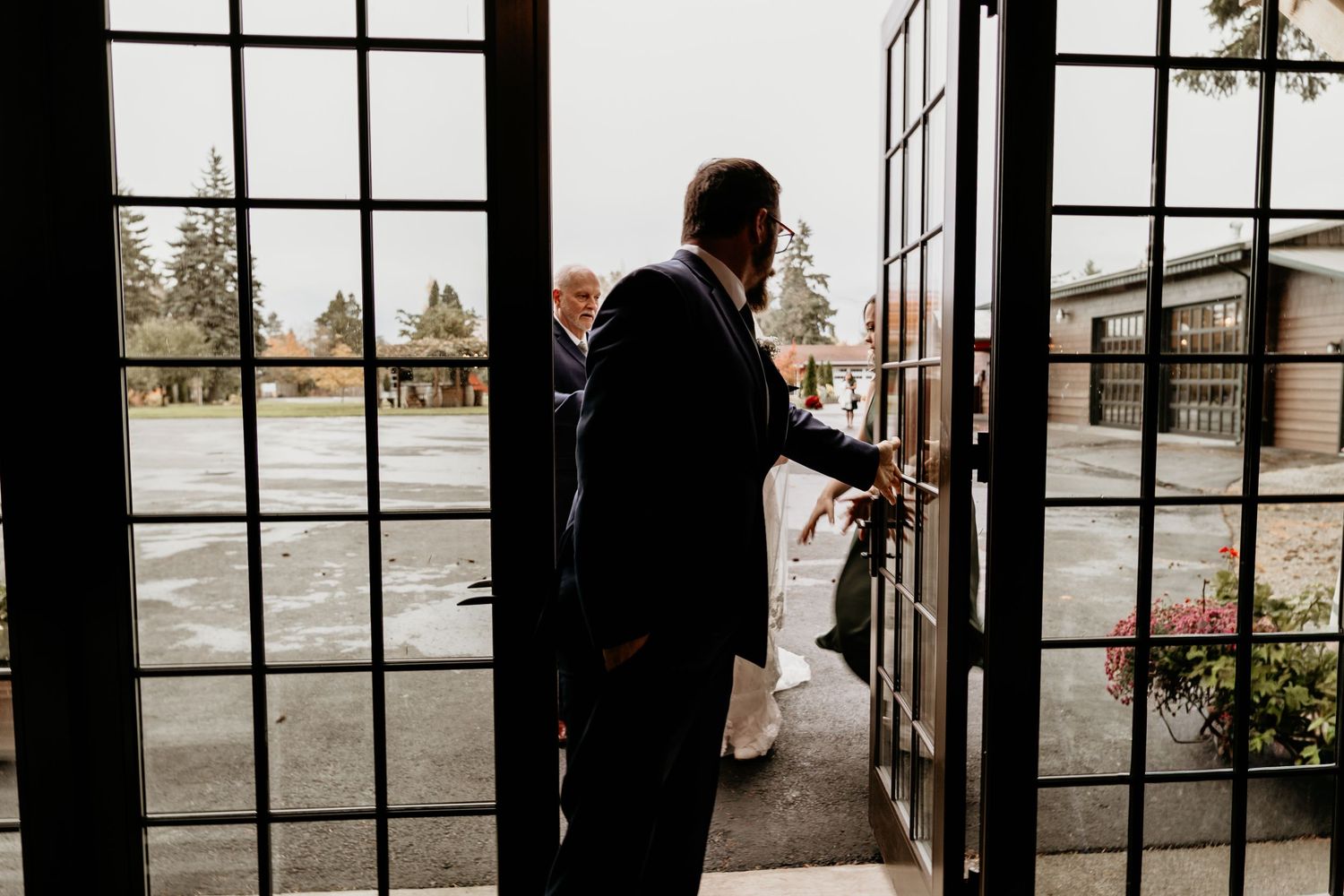 Wedding guest opening ornate iron doors at a wedding venue on a cloudy day.