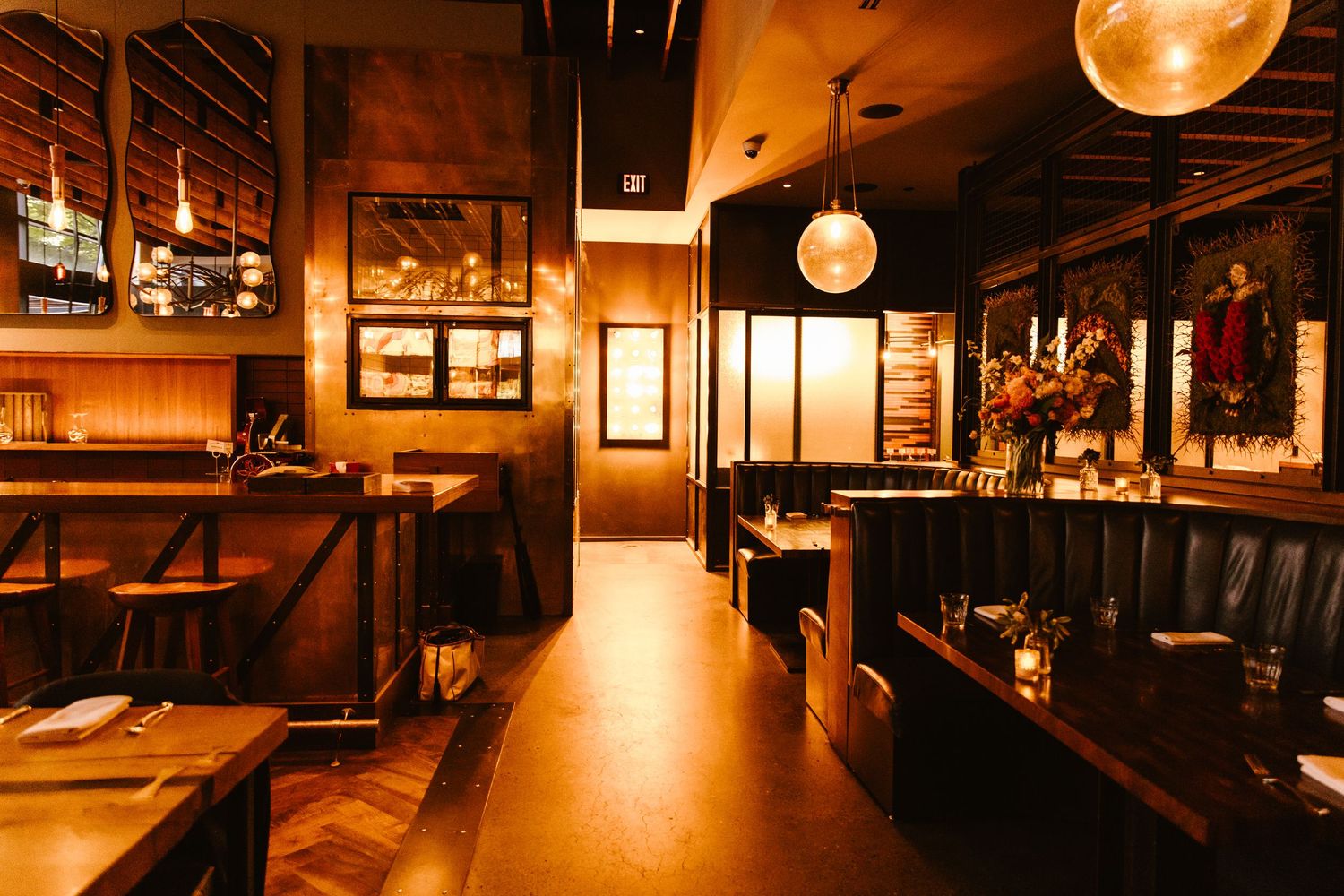 Warm, dimly lit restaurant interior with wooden booths, framed artwork, and a glowing disco ball centerpiece.