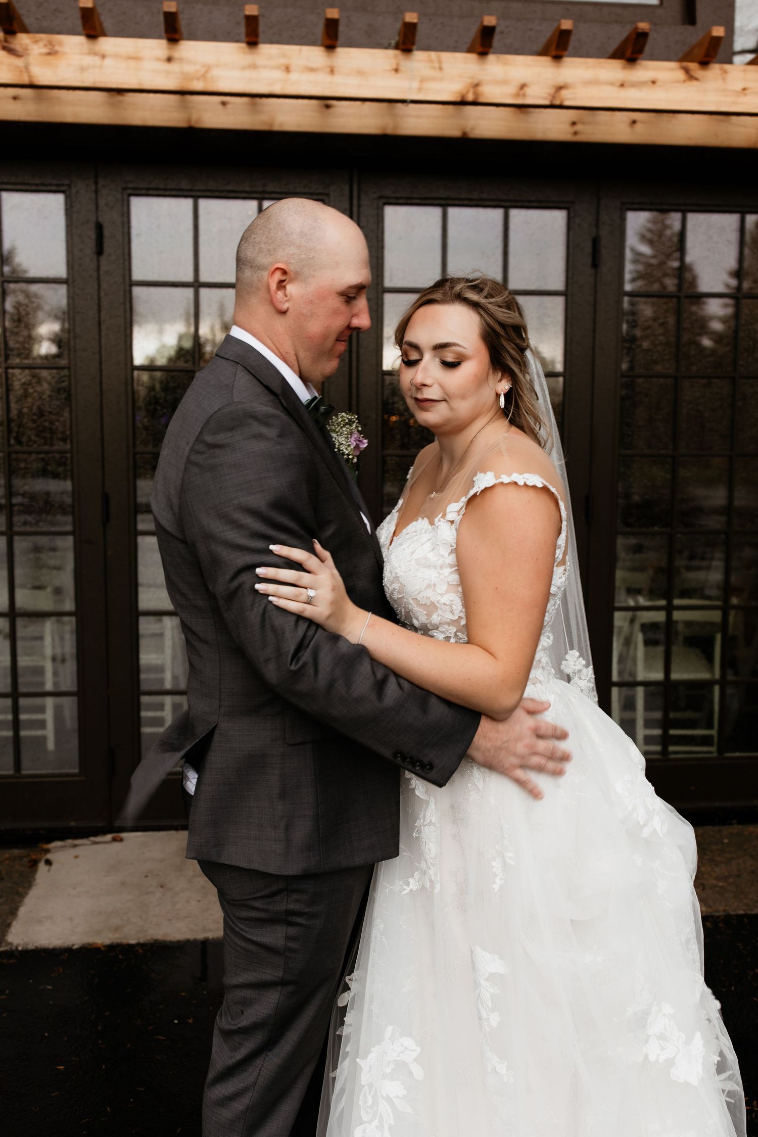 Bride and groom sharing a tender embrace outside elegant venue on their wedding day.