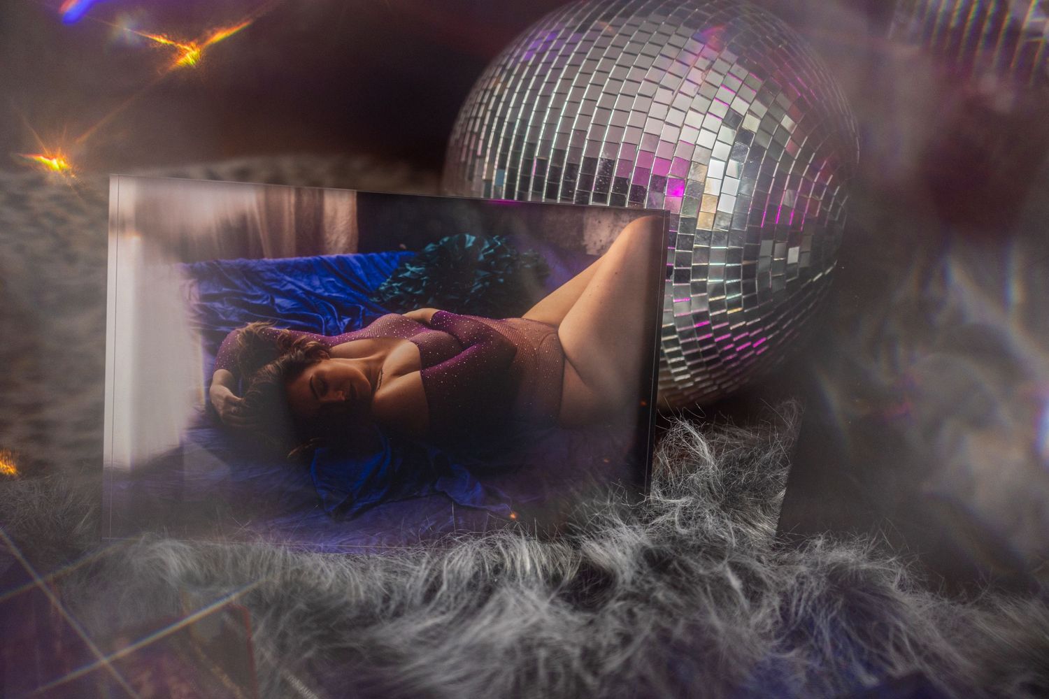 A dreamy boudoir ice block with a disco ball, fog effects, and a figure reclining in blue light at boudoir studio.