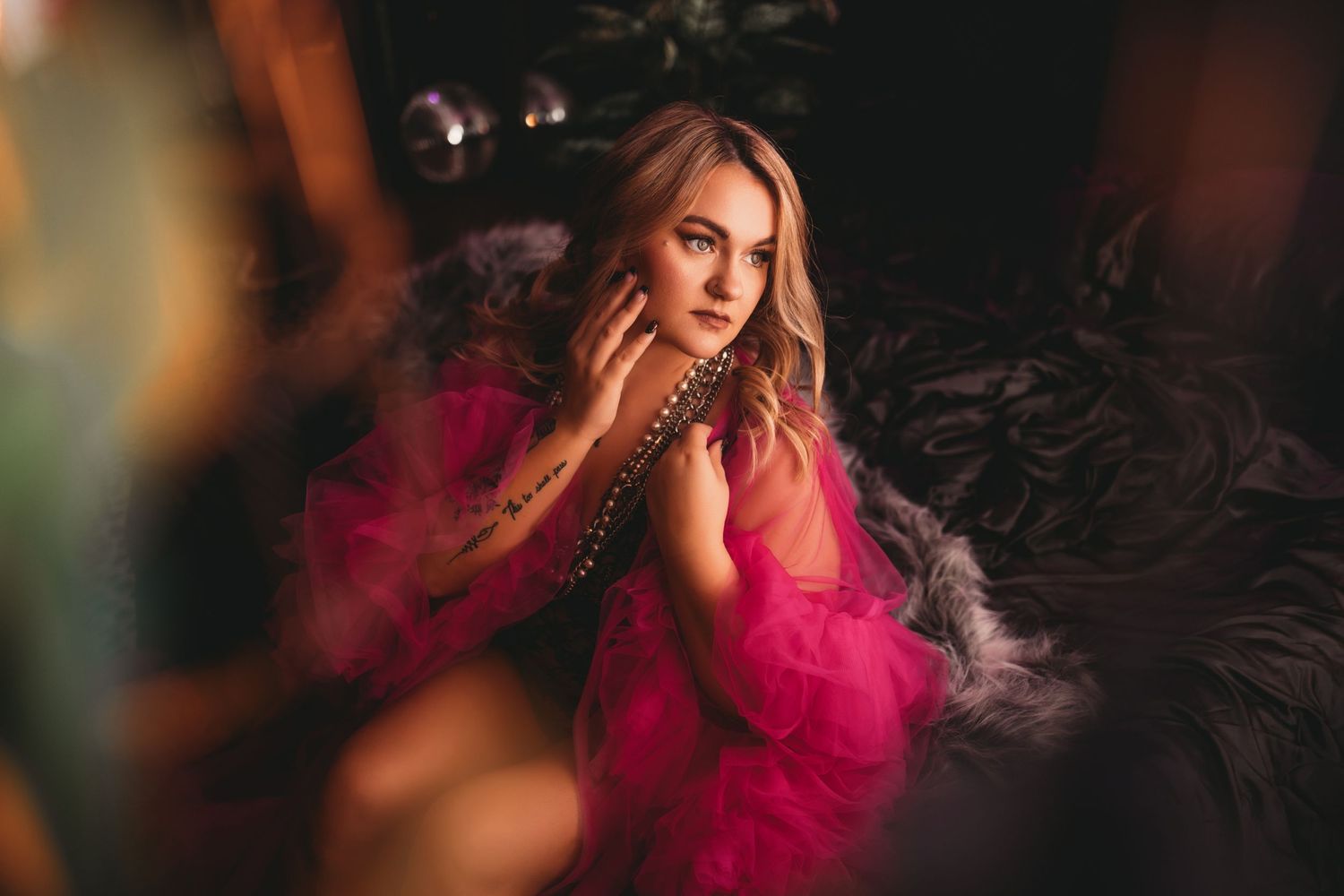 Boudoir image of a woman posing in a flowing pink robe surrounded by dreamy smoke effects and atmospheric lighting.