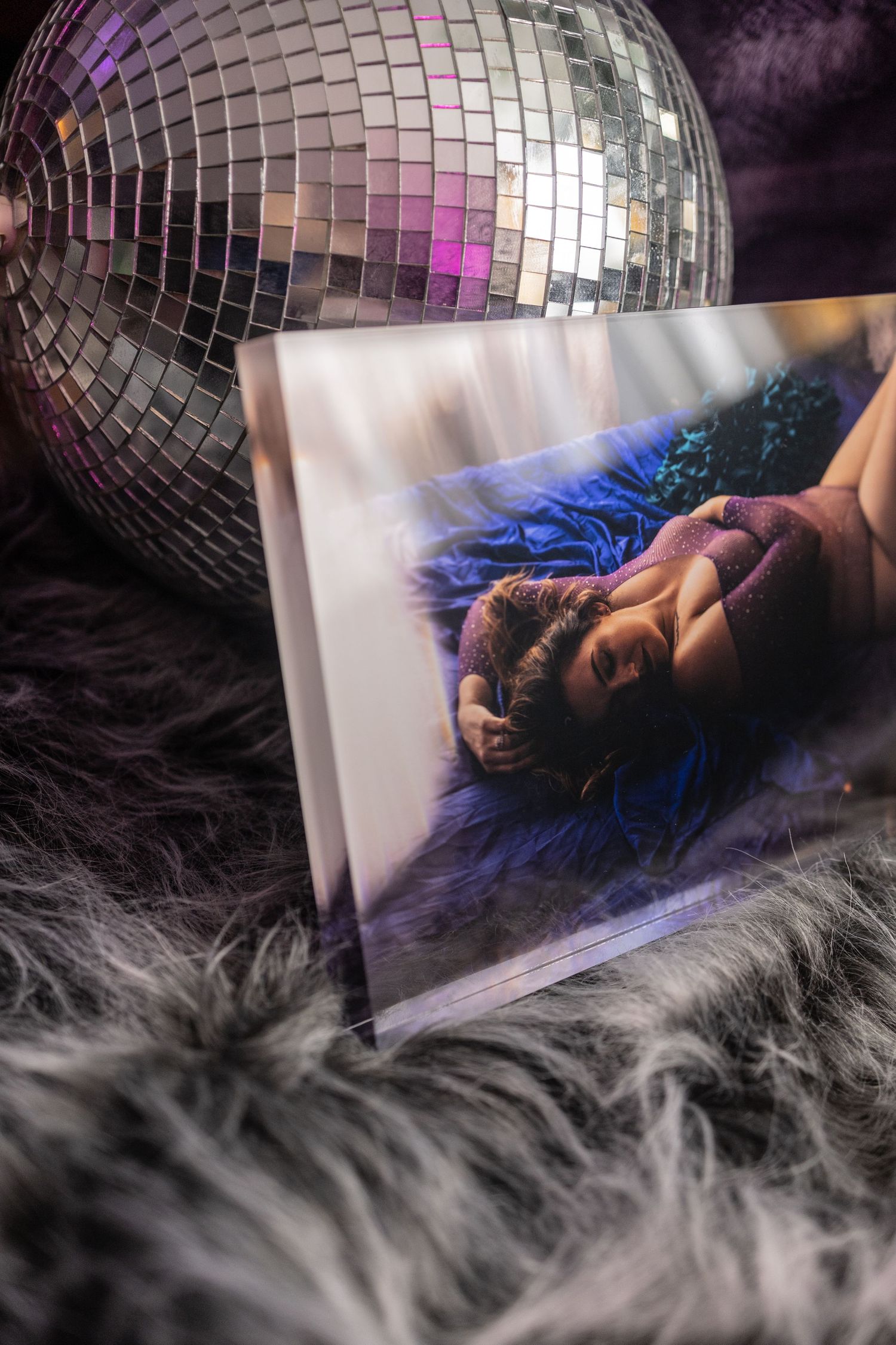 A dreamy boudoir ice block with a disco ball, fog effects, and a figure reclining in blue light at boudoir studio.