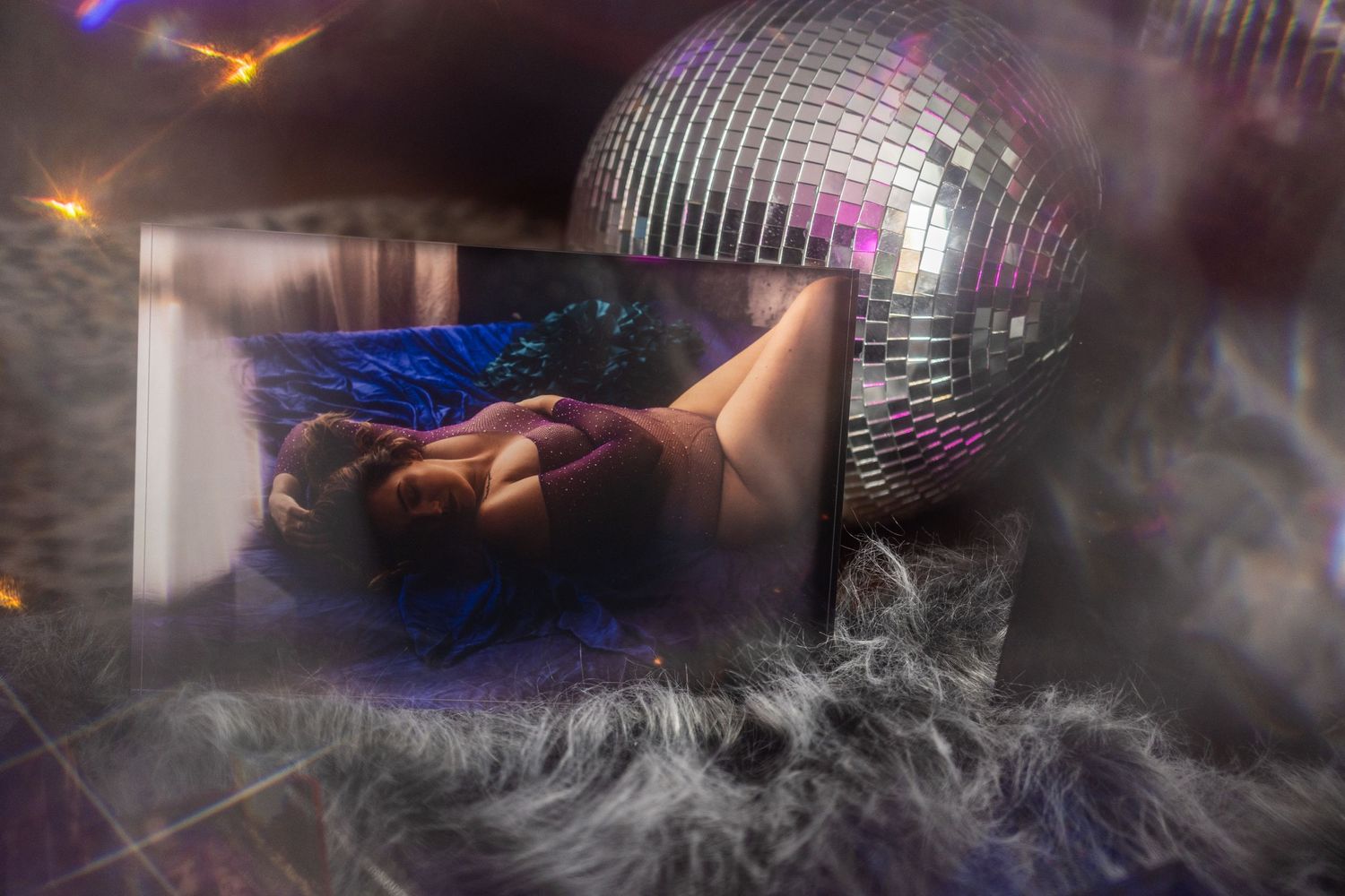 A dreamy boudoir ice block with a disco ball, fog effects, and a figure reclining in blue light at boudoir studio.