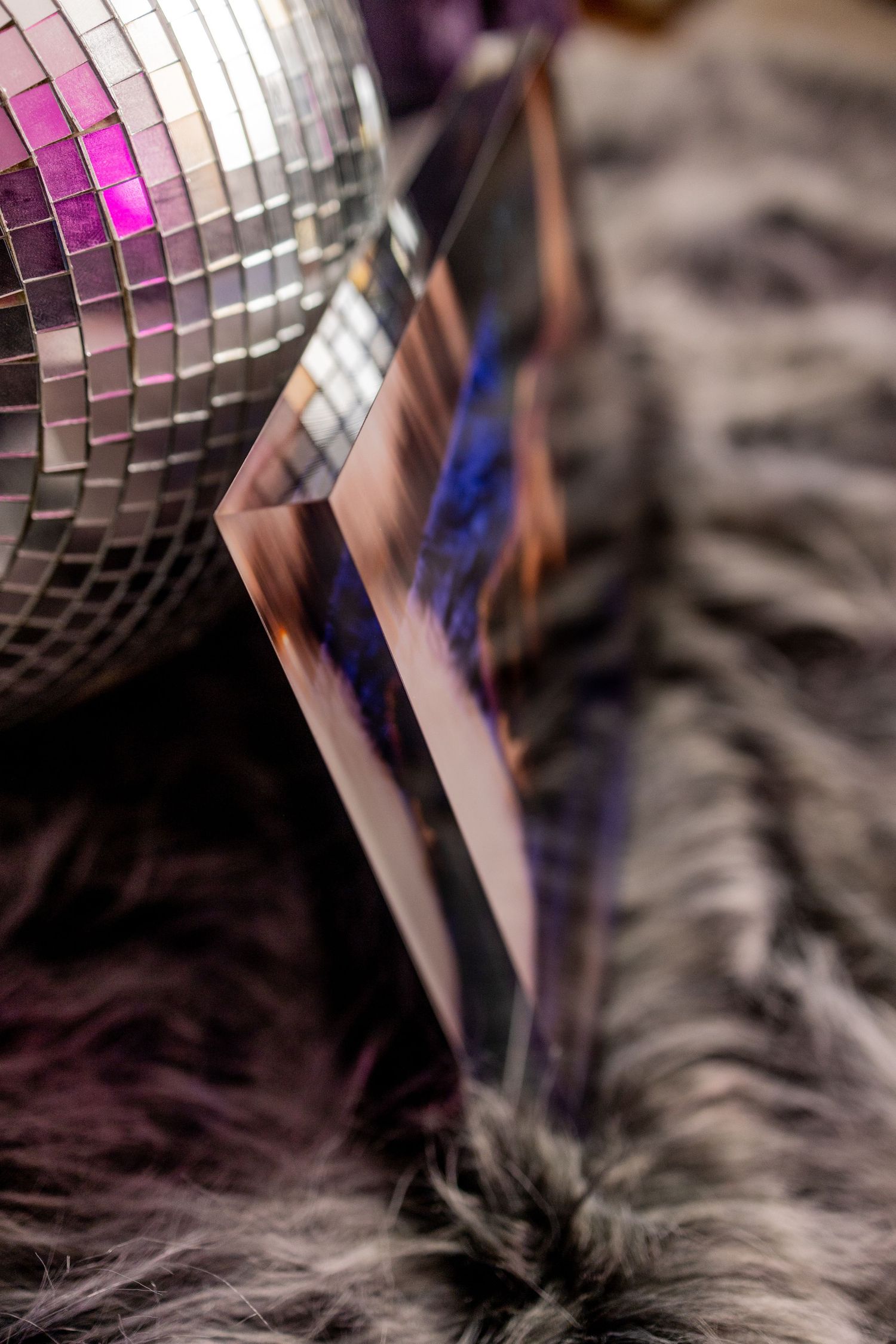 A dreamy boudoir ice block with a disco ball, fog effects, and a figure reclining in blue light at boudoir studio.