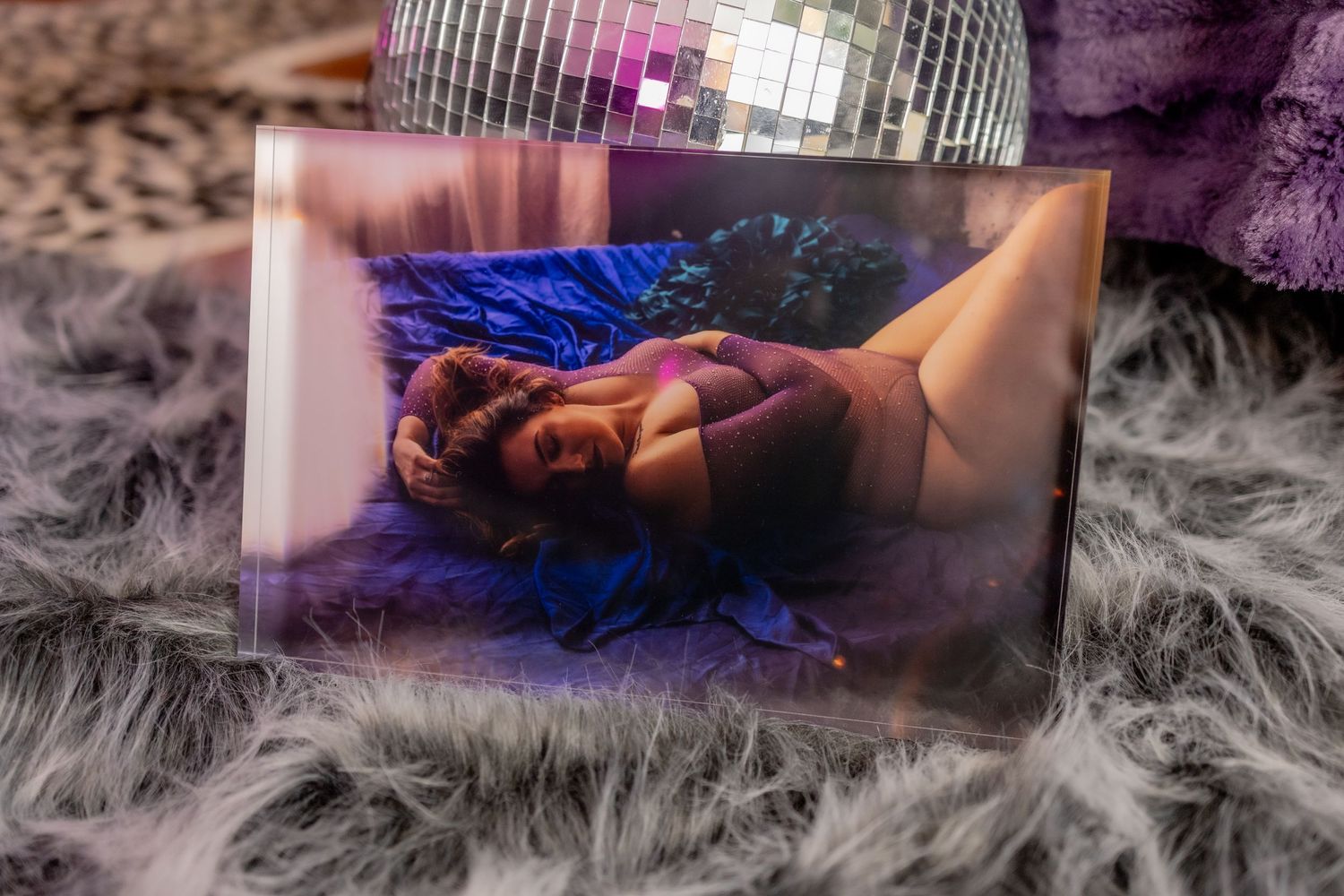 A dreamy boudoir ice block with a disco ball, fog effects, and a figure reclining in blue light at boudoir studio.