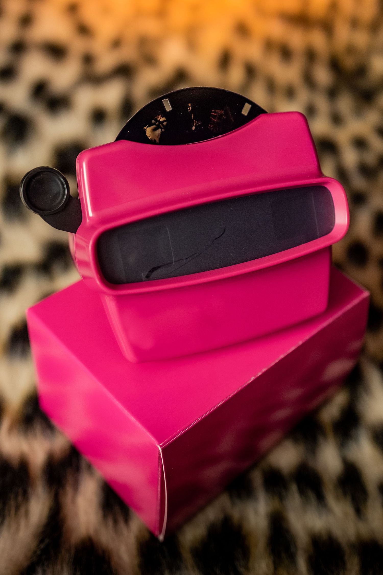 Pink retro Boudoir View-Master 3D viewer and its matching box photographed against a blurred leopard print background.
