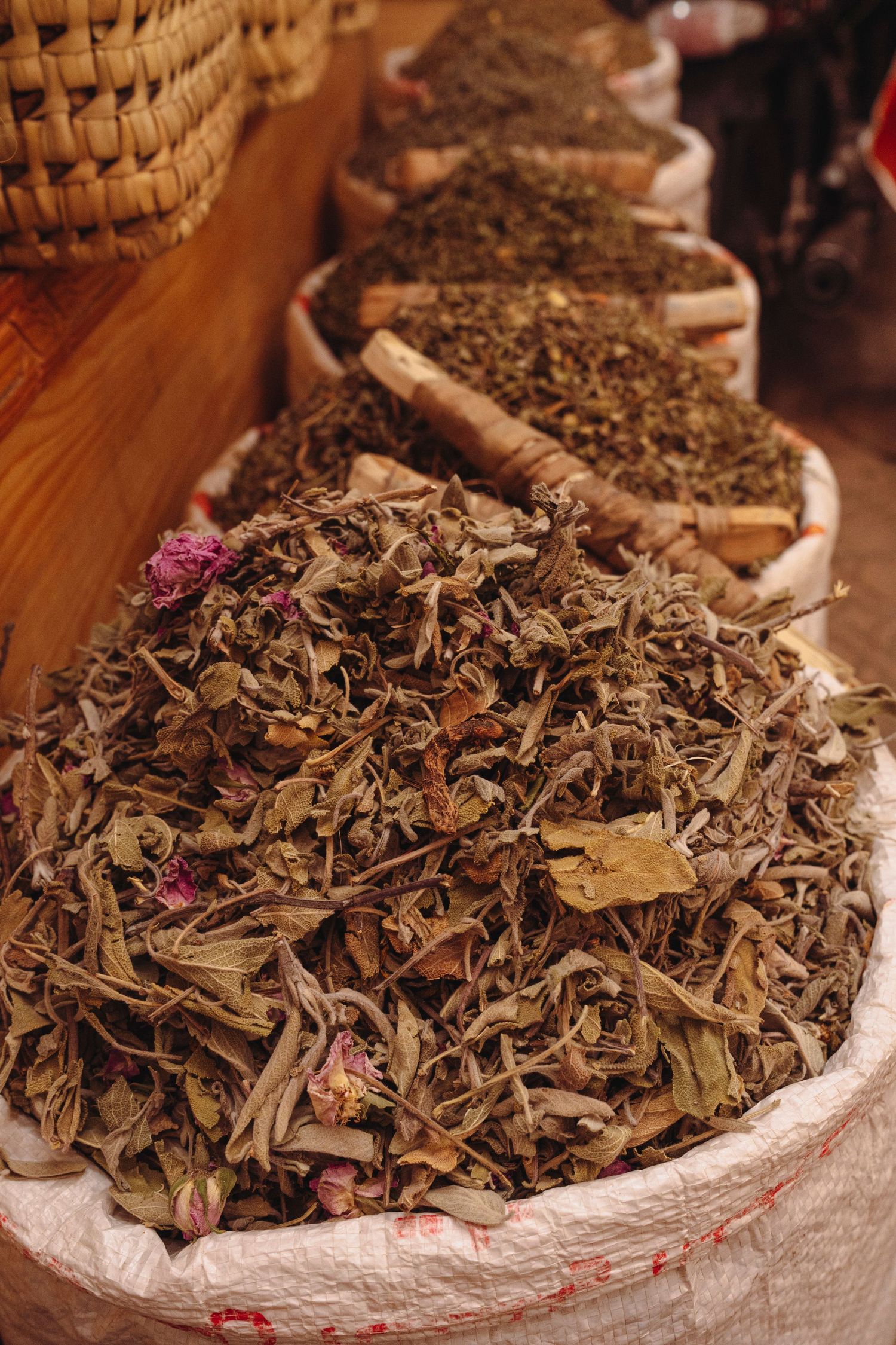 Dried herbal tea leaves and petals displayed in bulk on a wooden surface with natural lighting.