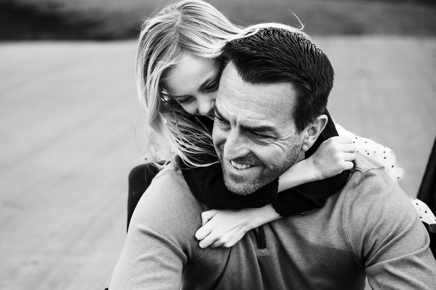 Daughter hugging her dad from behind during a candid family photo session