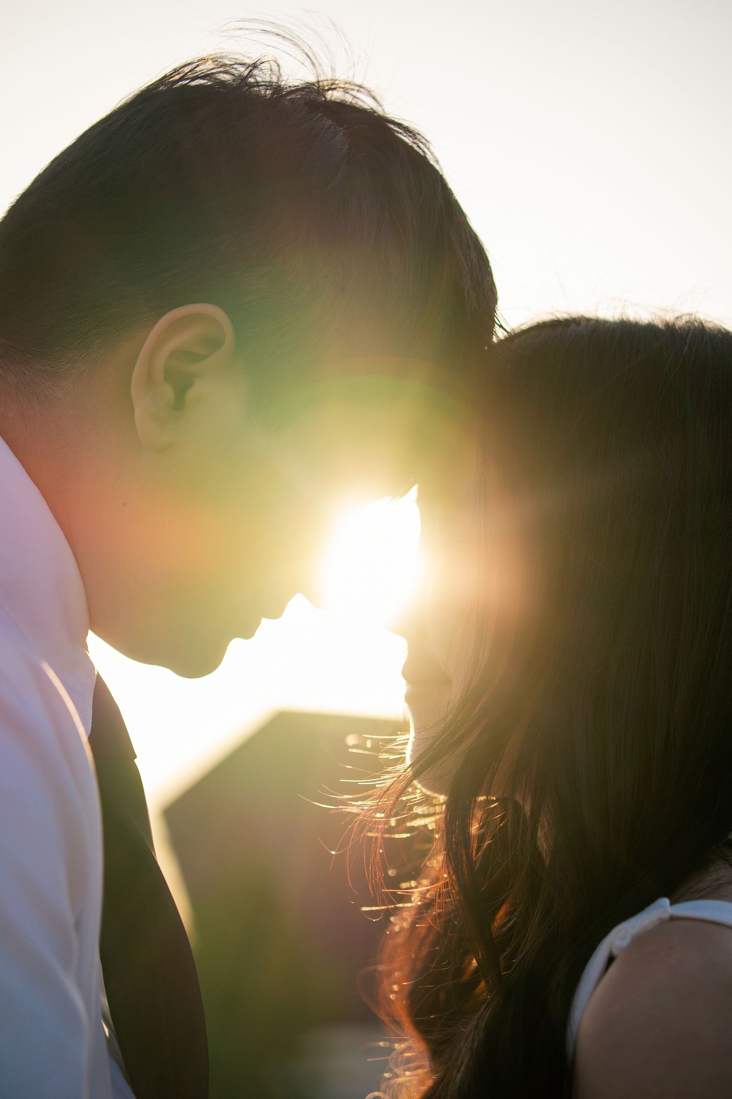 A romantic silhouette of a couple against bright sunlight creating a warm backlit glow at sunset.