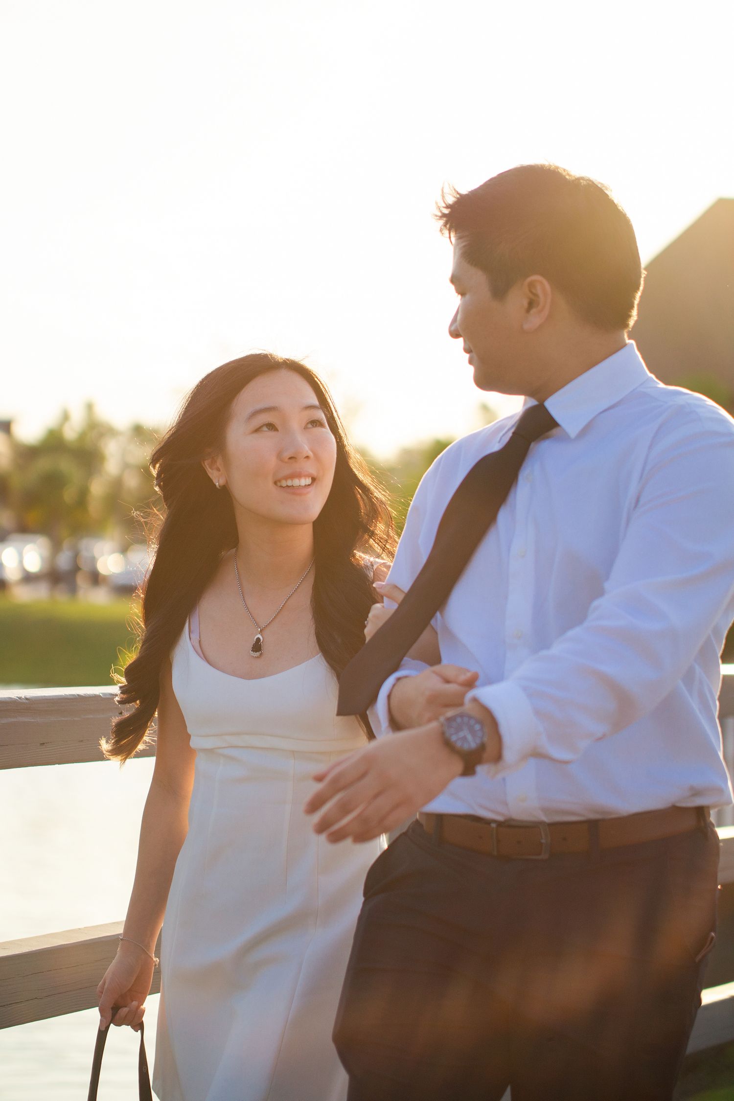 A couple shares tender moments at sunset by the water in a romantic engagement photoshoot series.