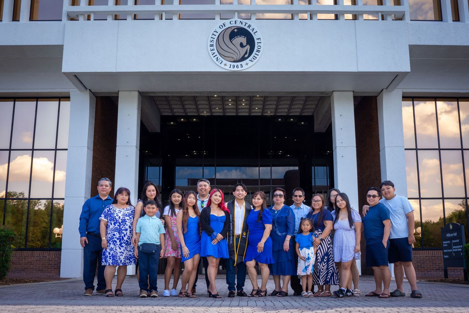 Large group of graduates and family members posing together outside a university building entrance.