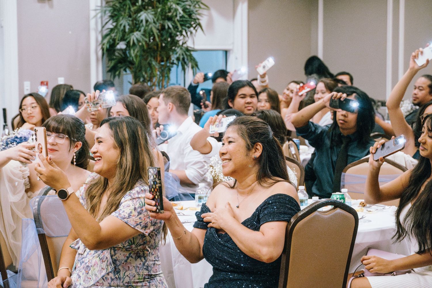 An energetic crowd of party guests cheering and celebrating in a banquet hall.
